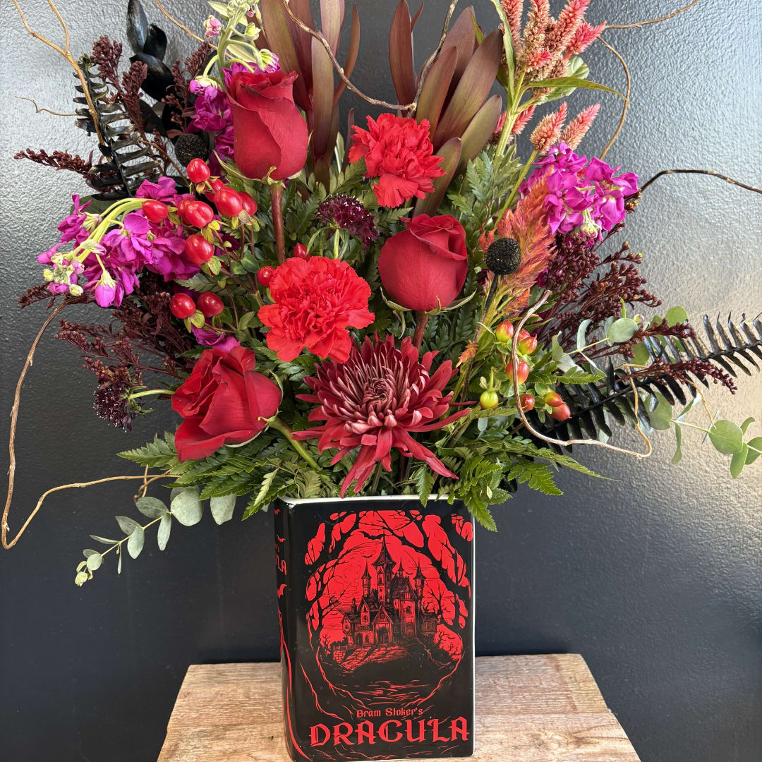 Red and purple floral arrangement in a Dracula-themed vase