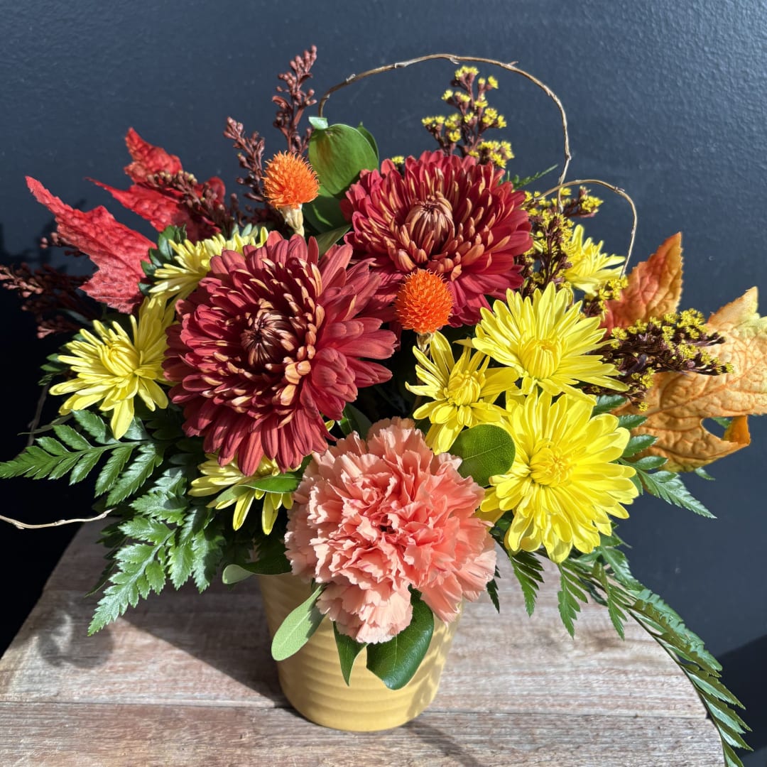 Bouquet of red and yellow chrysanthemums with a peach carnation in a yellow vase