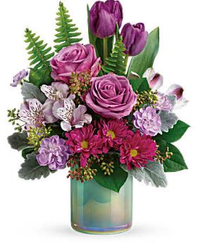Purple roses and tulips in a glass vase with mixed pink flowers