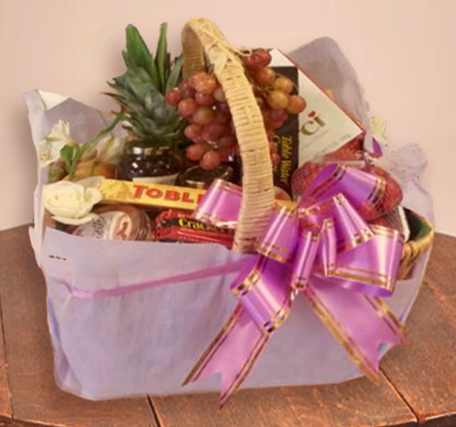 Gift basket with fruit, chocolates, and a purple ribbon