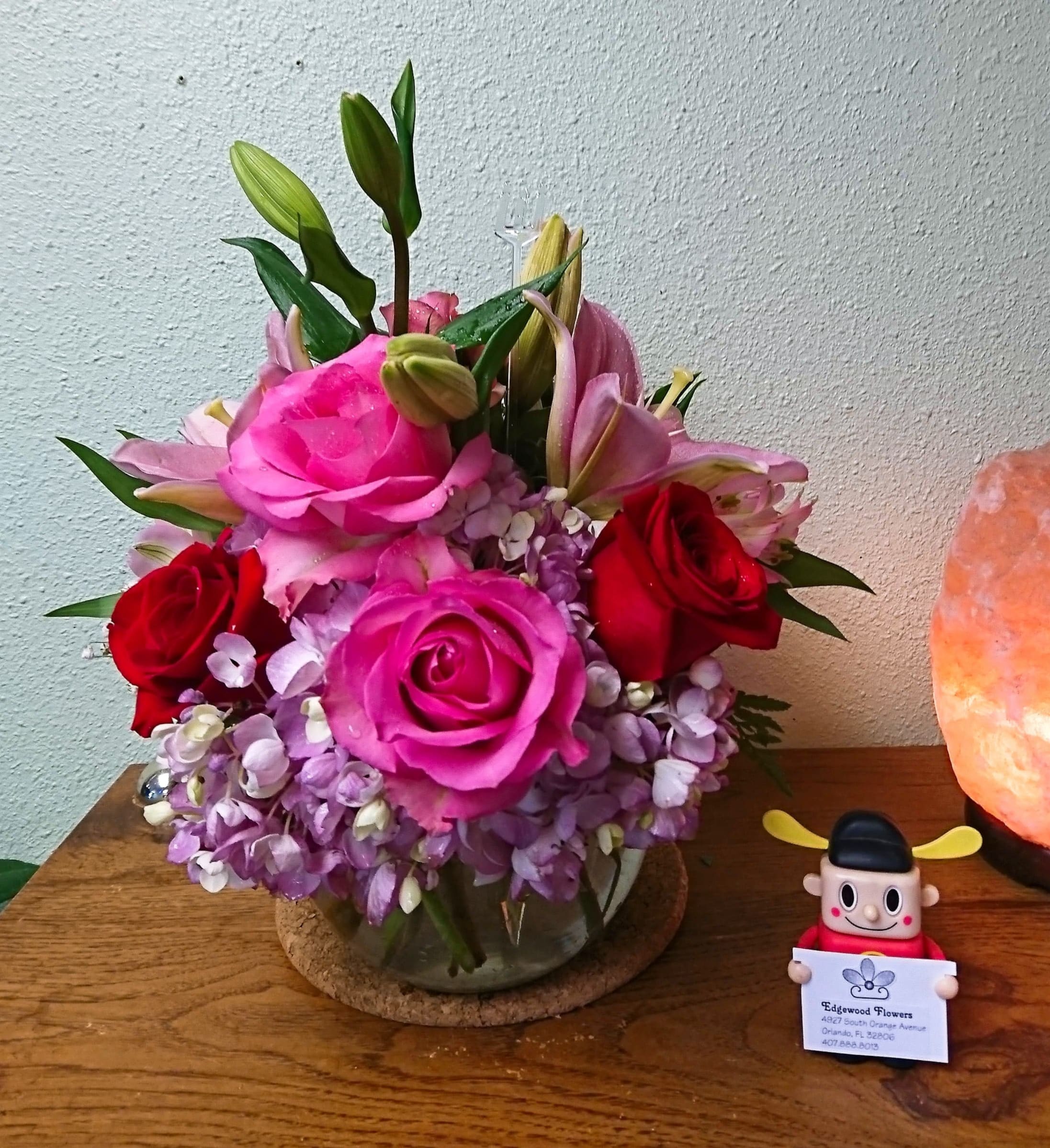 Pink and red roses with lilies in a glass vase