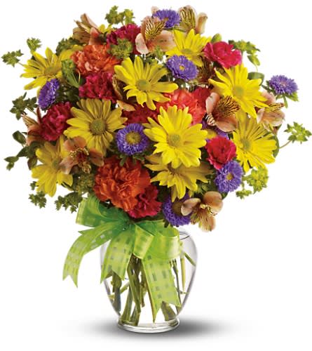Mixed bouquet of yellow, red, and purple flowers in a glass vase with a green ribbon