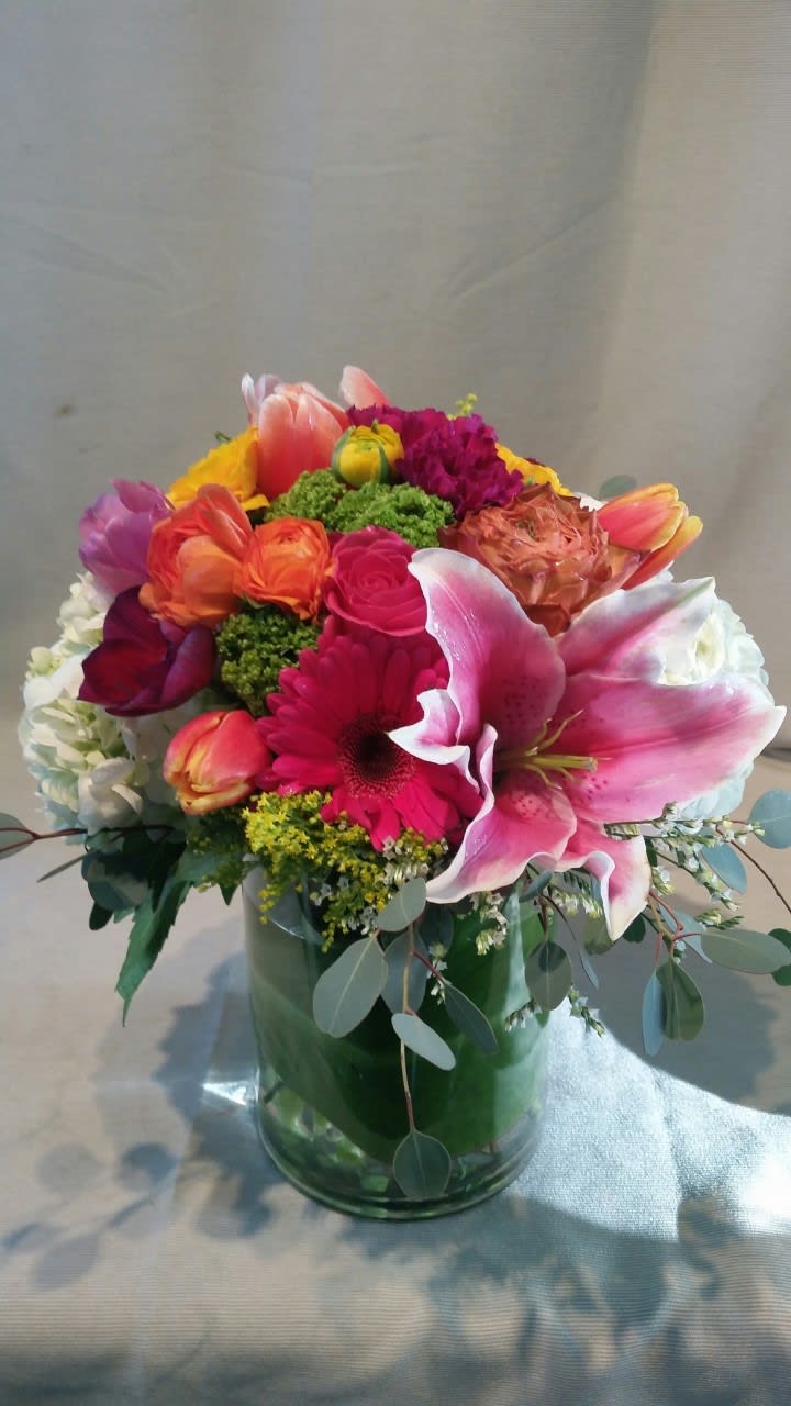Colorful mixed bouquet in a glass vase with a large pink lily