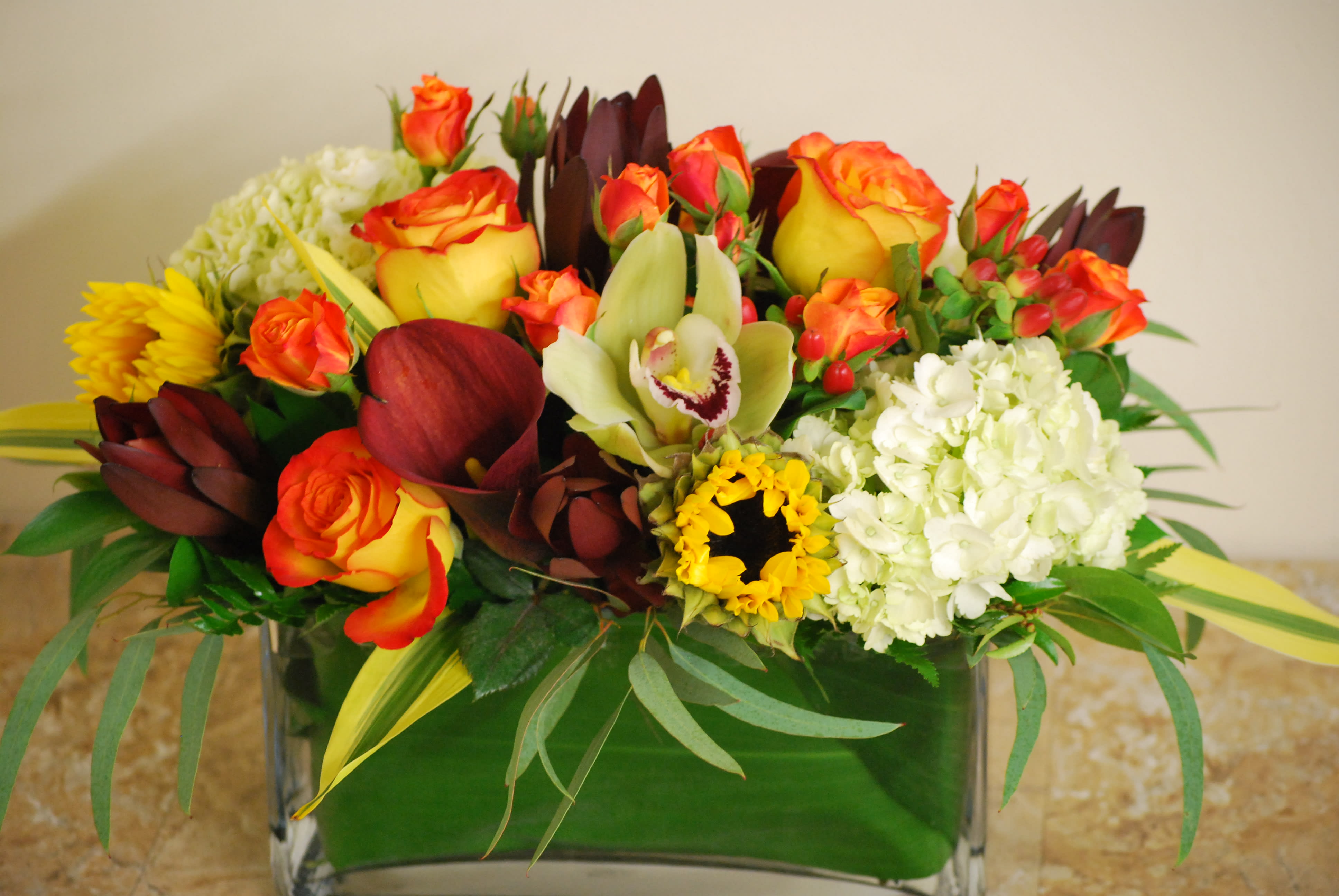 Mixed floral arrangement in a glass vase with orange roses and white hydrangeas