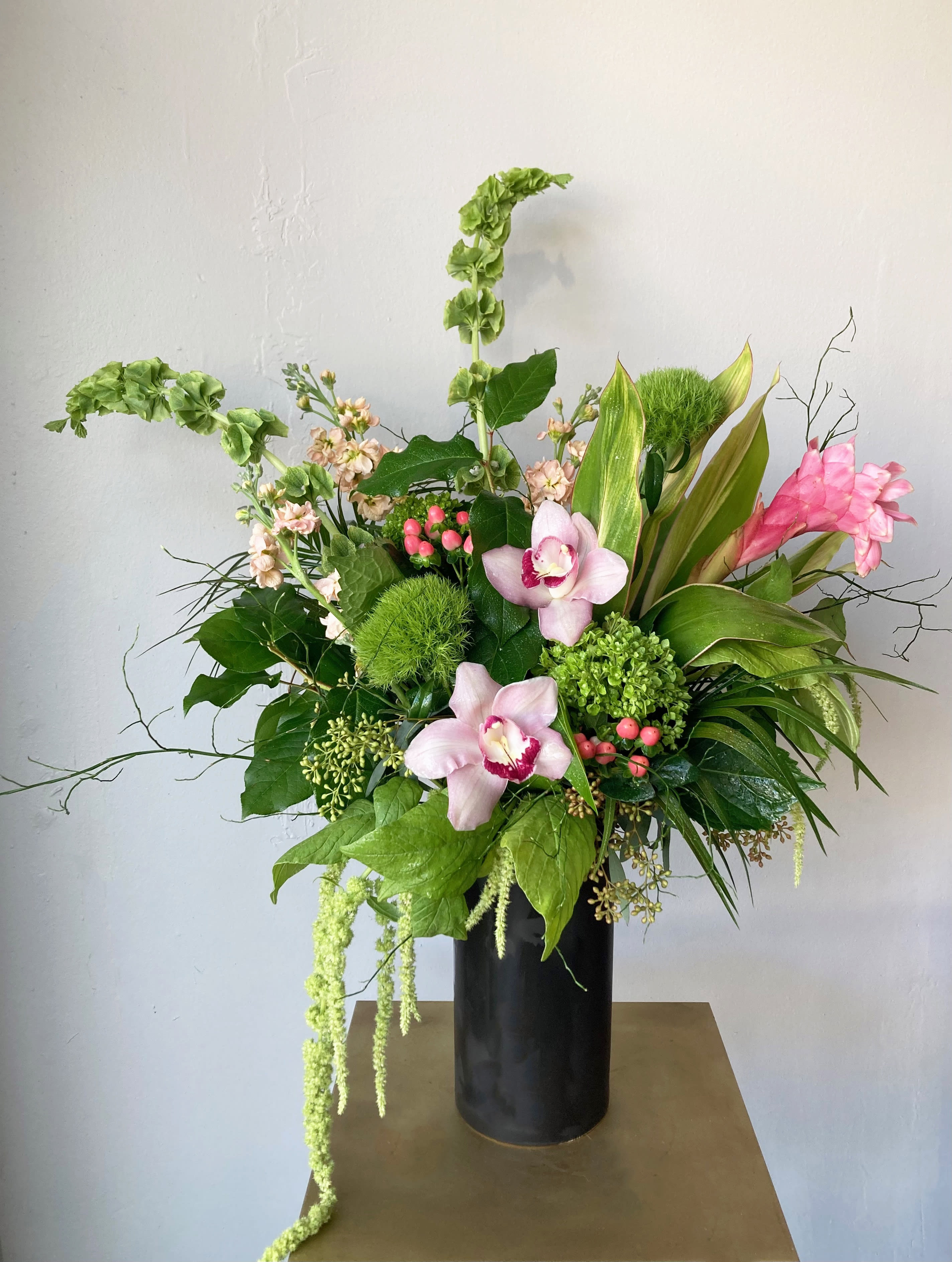 Tall floral arrangement with pink orchids in a black vase