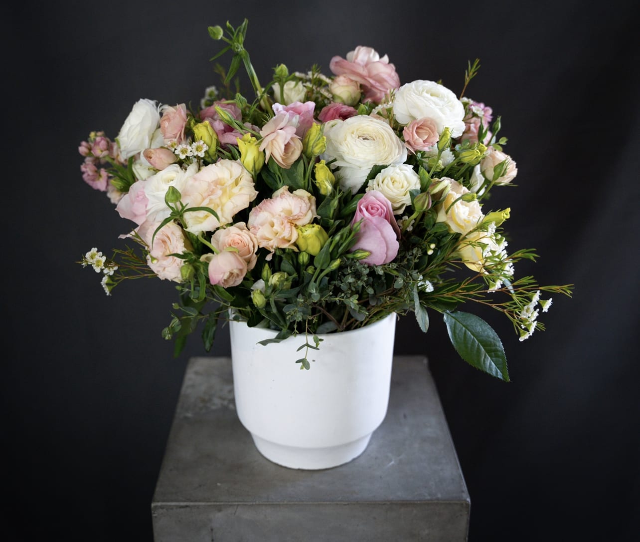 Pastel bouquet of roses and ranunculus in a white vase