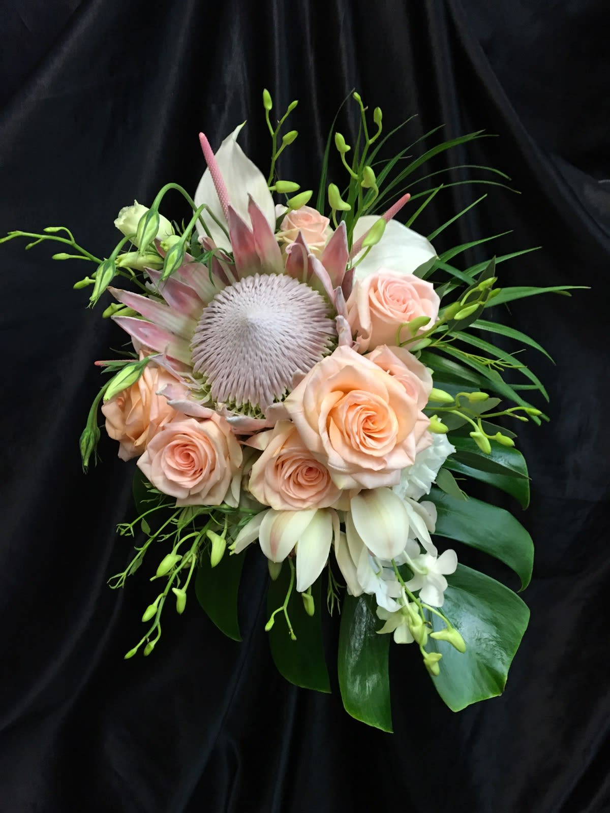 UNSTRUCTURED TROPICAL CLUTCH 1 - KING PROTEA, LIGHT PEACH ROSES, WHITE DENDROBIUM ORCHID SPRAYS, MONSTERIA &amp; ARECA PALM LEAVES