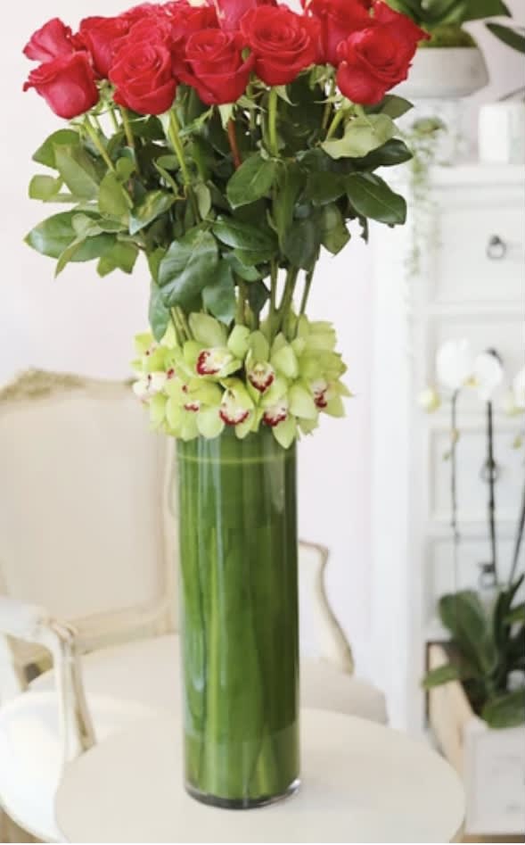 Tall vase arrangement of red roses with green orchids