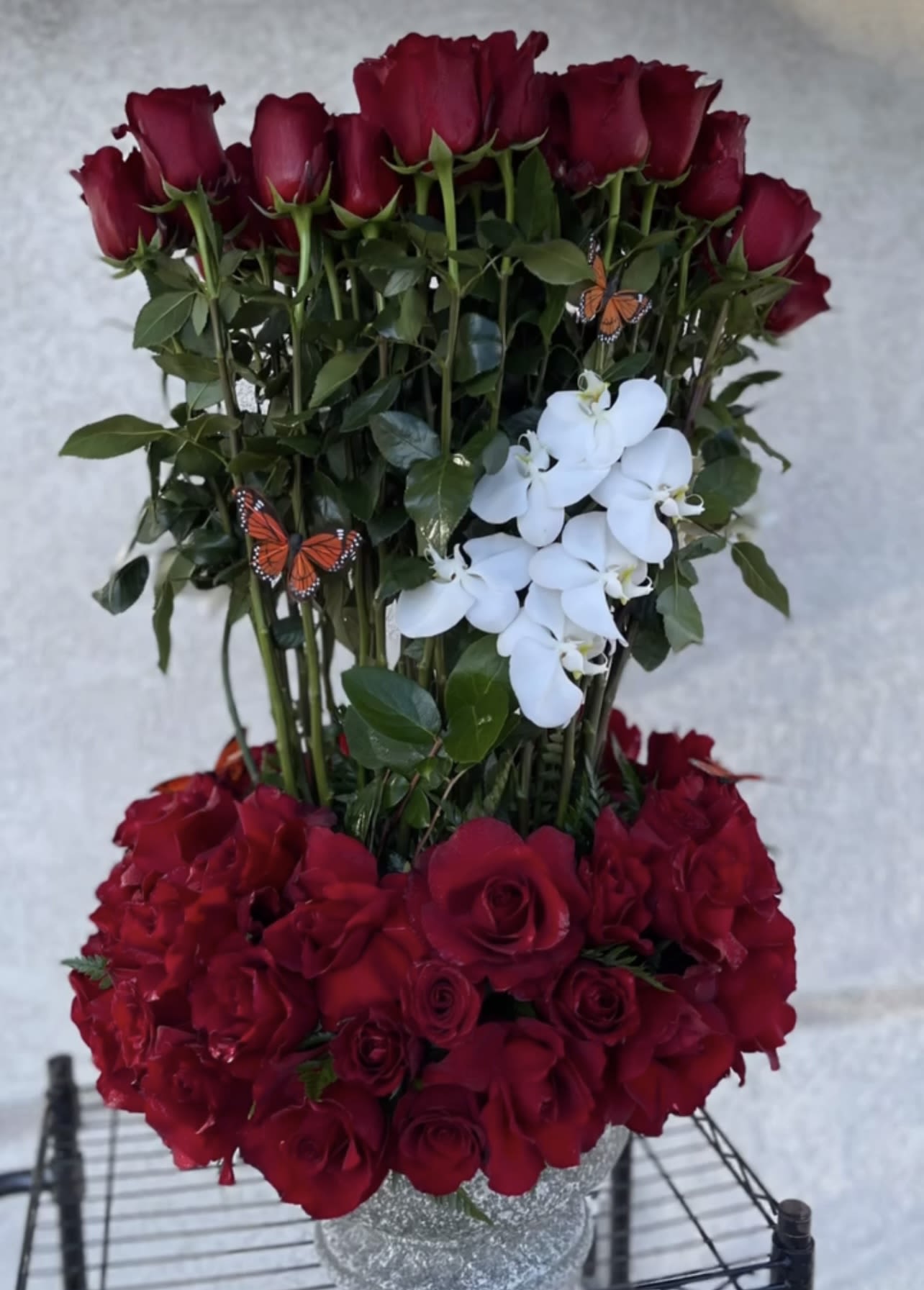 Tall red rose arrangement with white orchids in a silver vase
