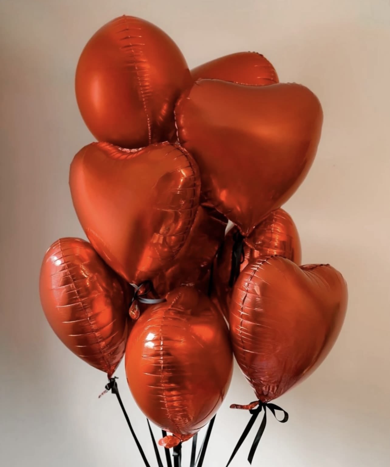 Cluster of red heart-shaped balloons tied with black ribbons