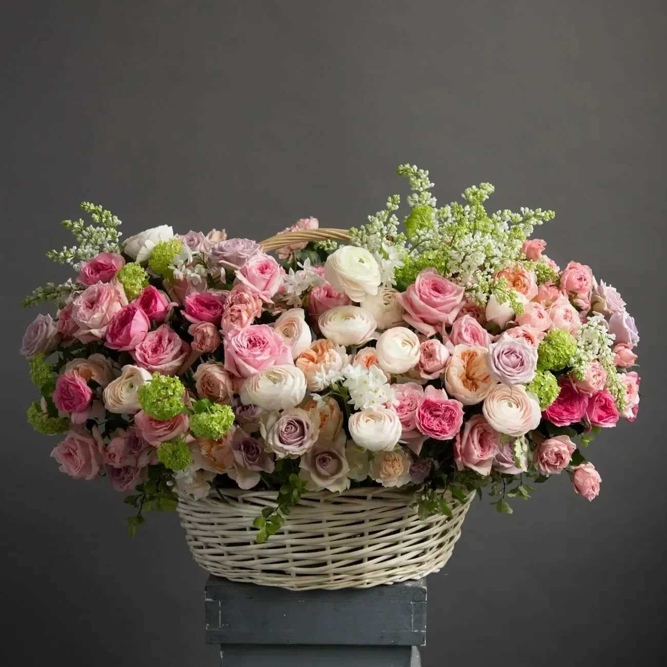 Large basket of pink and peach roses and ranunculus with soft white and green accents