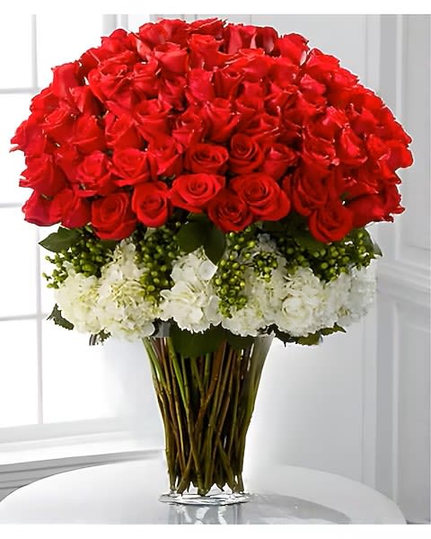 Large bouquet of red roses with white flowers in a clear glass vase