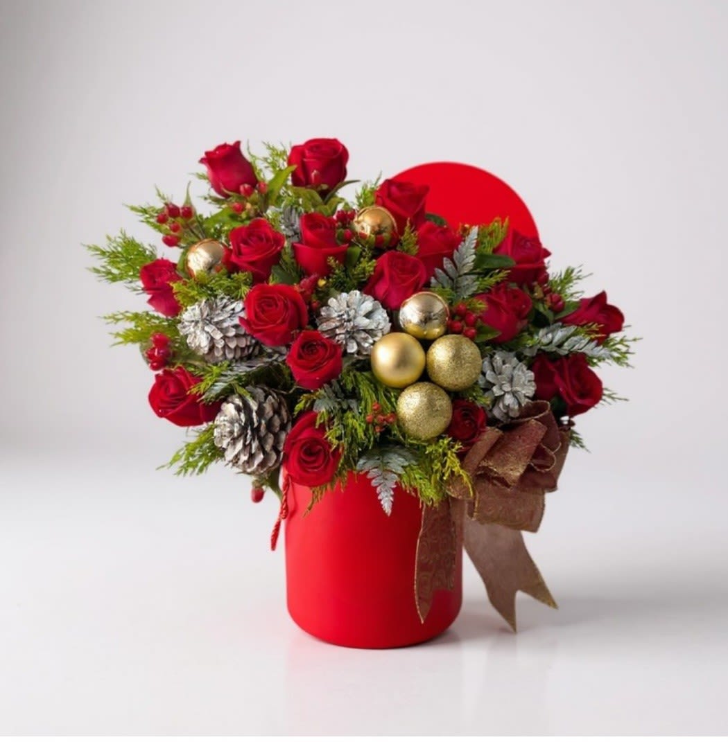 Red roses arranged in a red vase with gold ornaments and pinecones