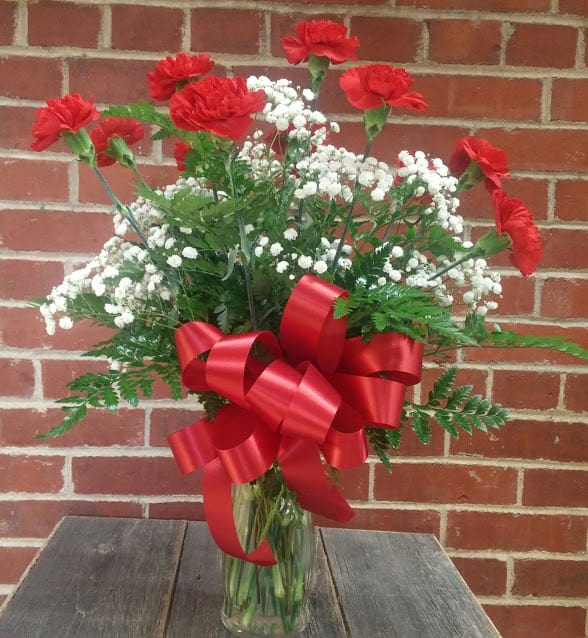 12 Red Carnations - A beautiful dozen red carnations with babies breath and greenery.  Give us a call and see what other colors we have in stock.