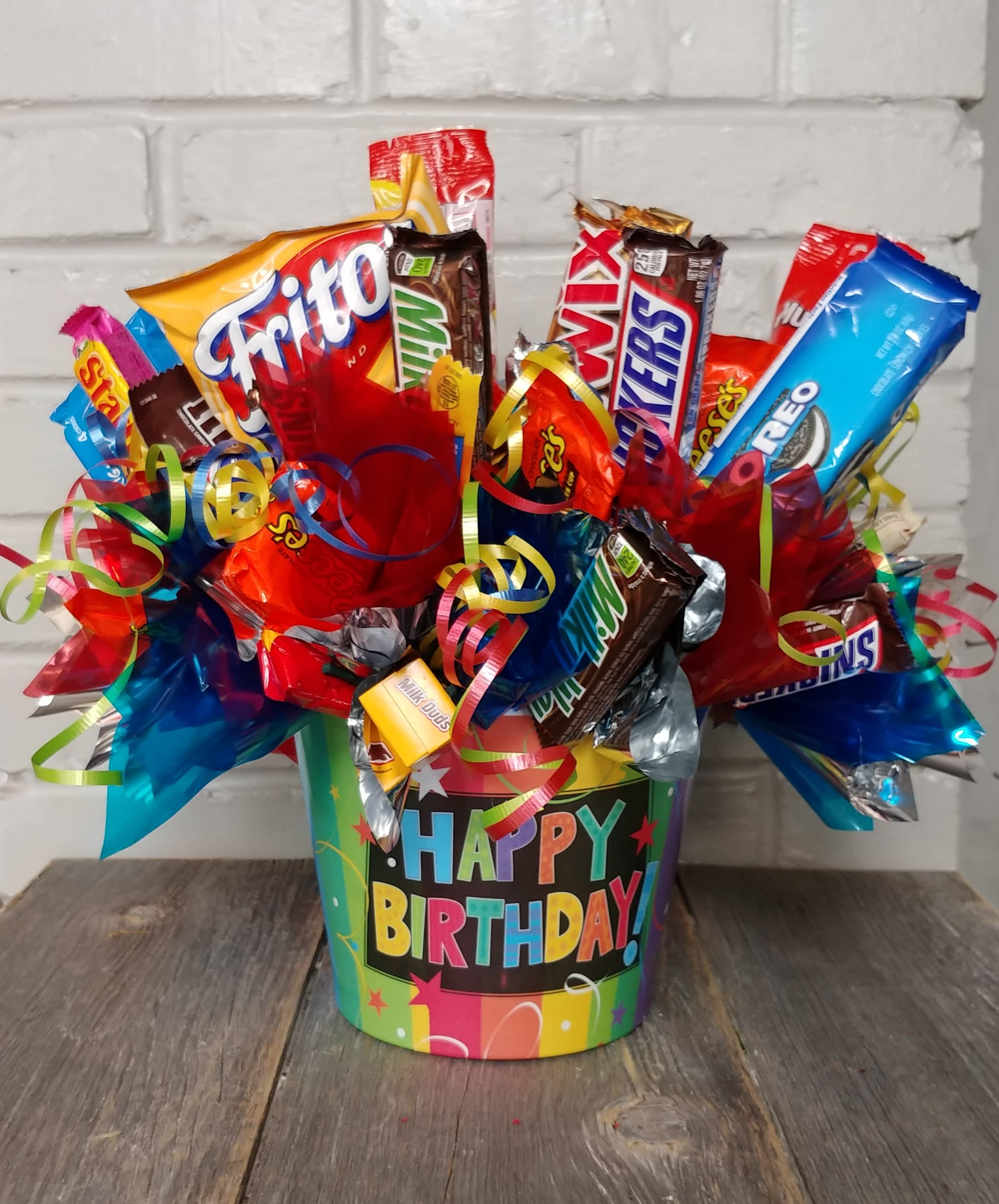 Birthday candy bouquet in a colorful bucket with assorted candy bars and ribbons.