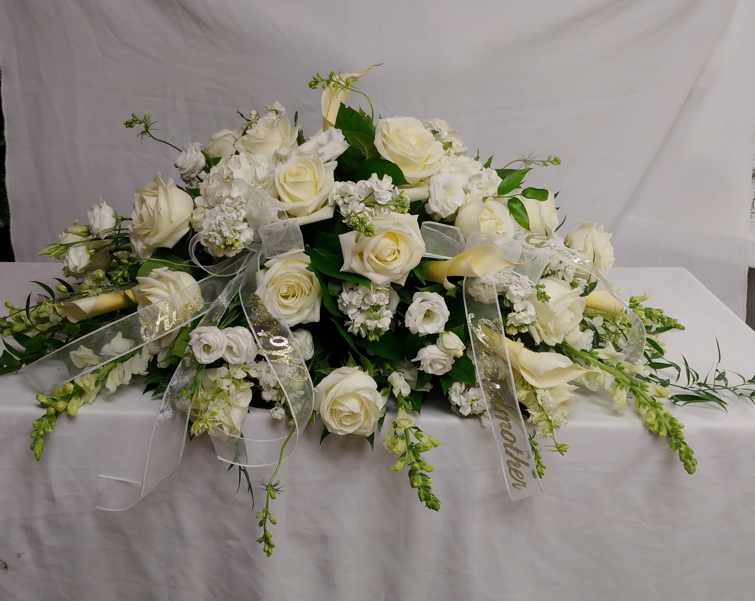 Bountiful Memories - A casket spray made of all white flowers and simple greenery is simply stunning. 