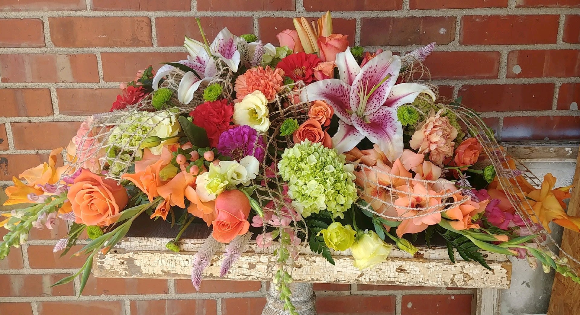 Large mixed floral arrangement with lilies, roses, and carnations in warm colors