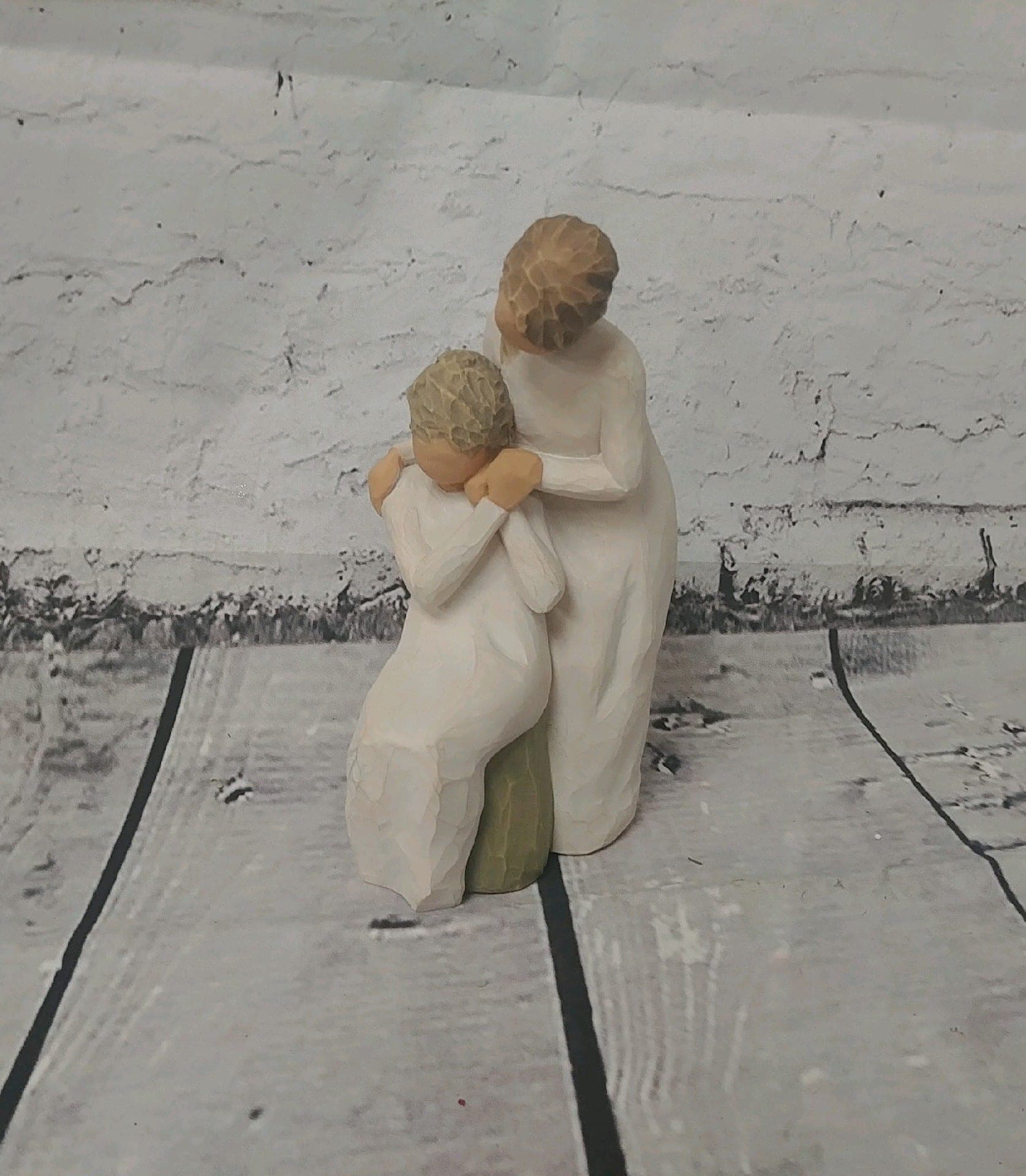 Two carved figurines of a woman and child in white robes