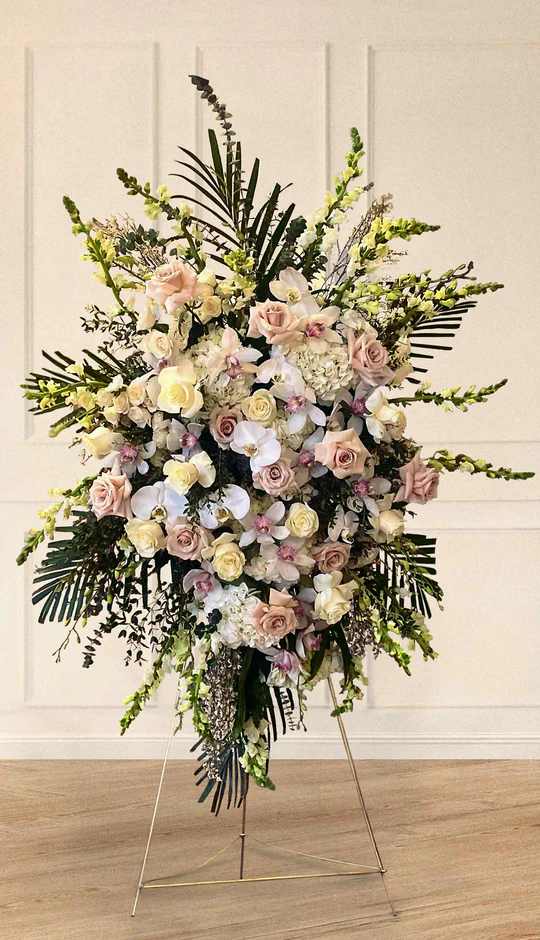 Large standing floral spray with pale roses and orchids on an easel