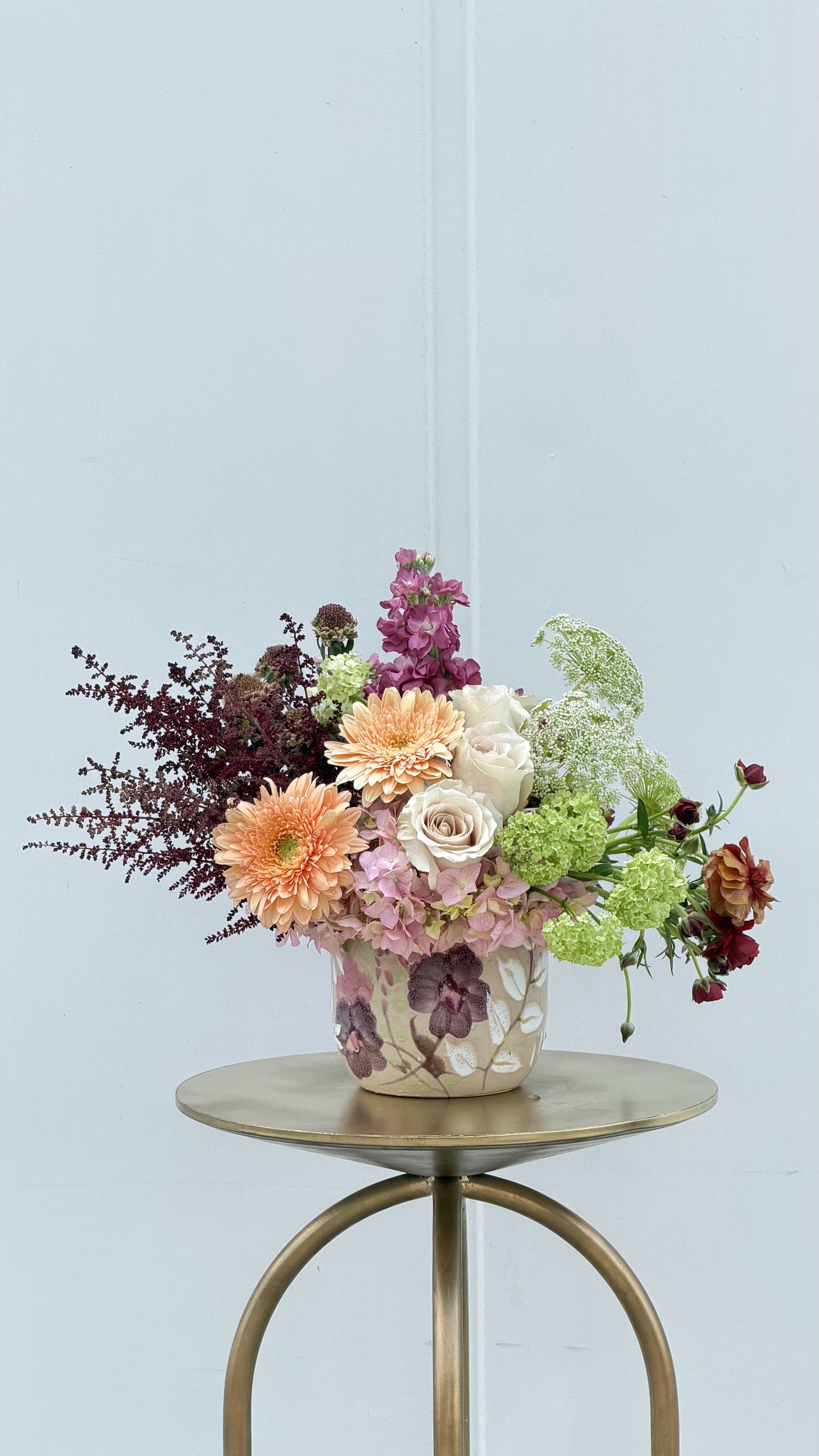 Mother Dearest - Soft, graceful, and full of heartfelt charm, Mother Dearest is a beautiful tribute to the ones who nurture us most. This thoughtfully designed arrangement features creamy ivory roses, peach gerbera daisies, and delicate pink hydrangea, accented with fresh green blooms and airy, textural florals for a naturally elegant look.  Designed in a floral keepsake vase with subtle botanical detailing, this piece blends warmth and sophistication—perfect for celebrating her with something as special as she is.  Mother Dearest is a timeless way to say thank you, I love you, and you mean everything—capturing the gentle beauty and strength of motherhood in every stem.  ***Limited quantity available***