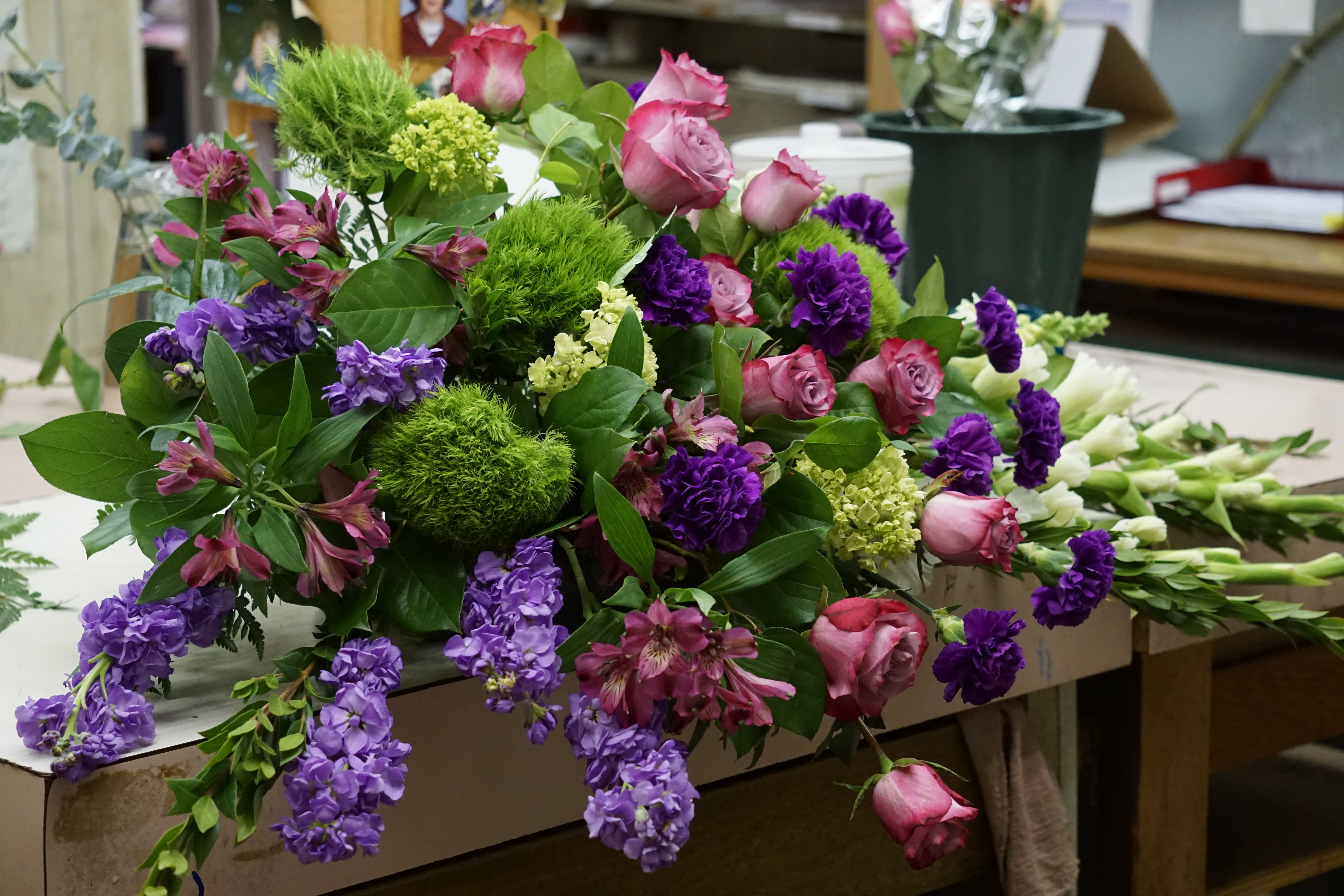 Mixed bouquet with pink roses, purple flowers, and green pom-pom blooms