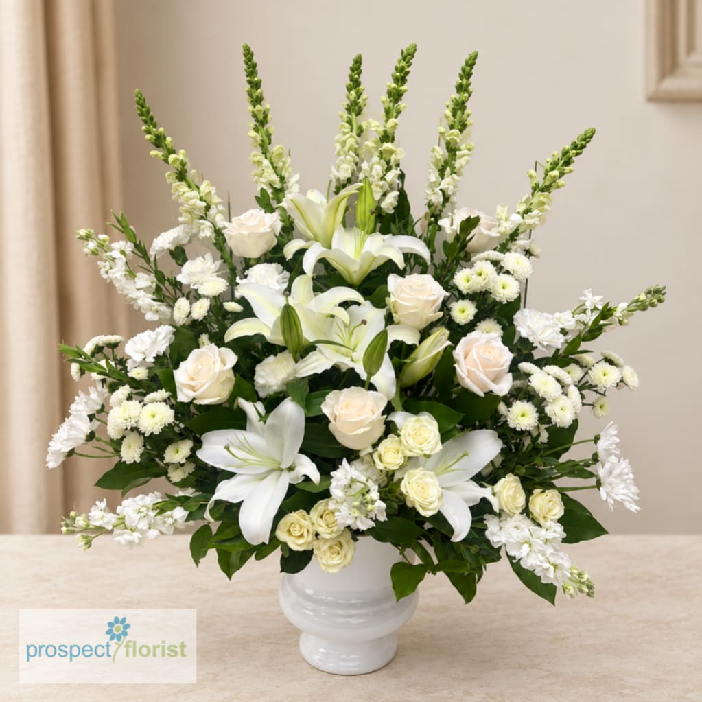 White lilies and roses arranged in a white vase