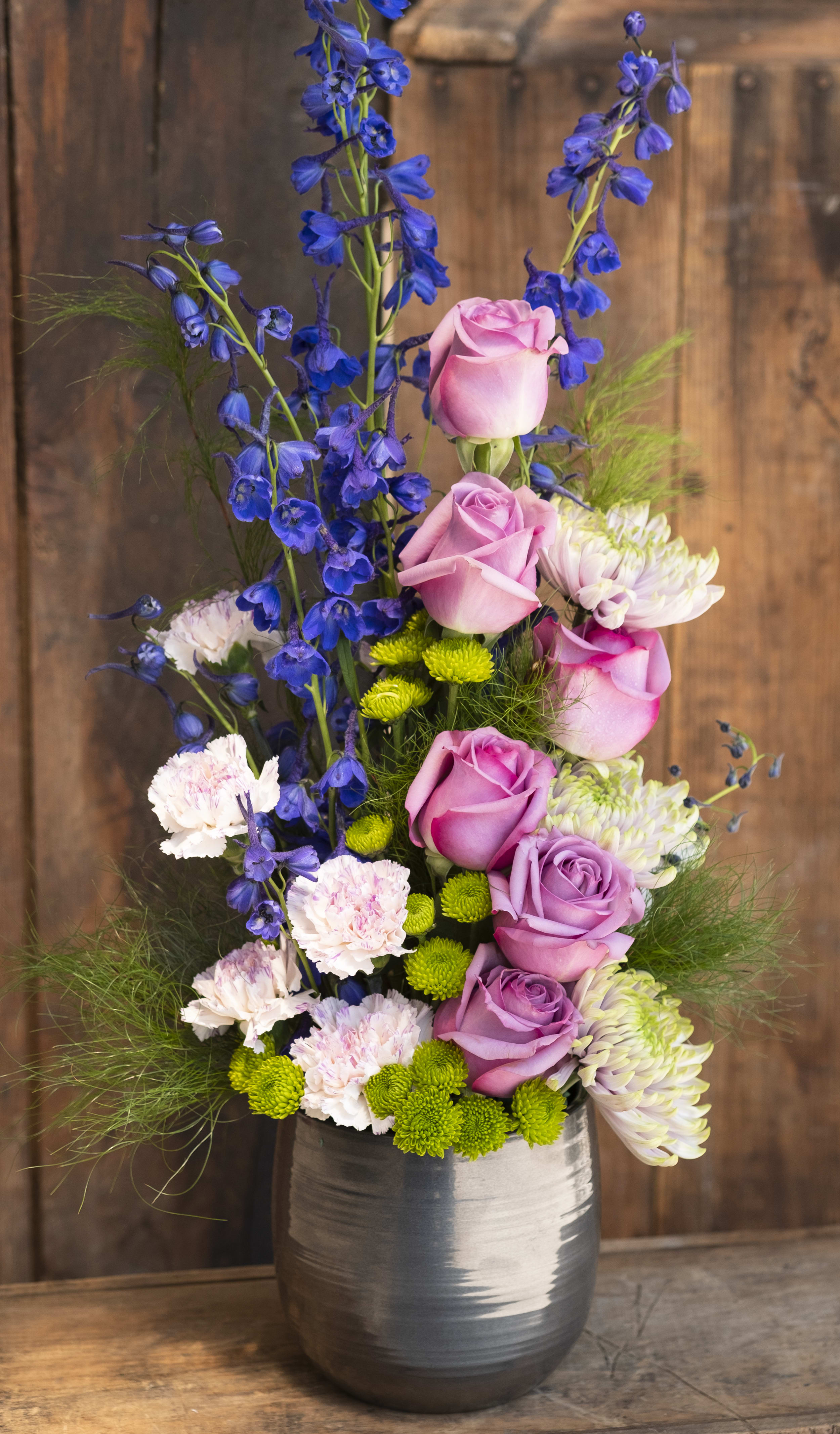 Pink roses and blue delphinium in a silver vase