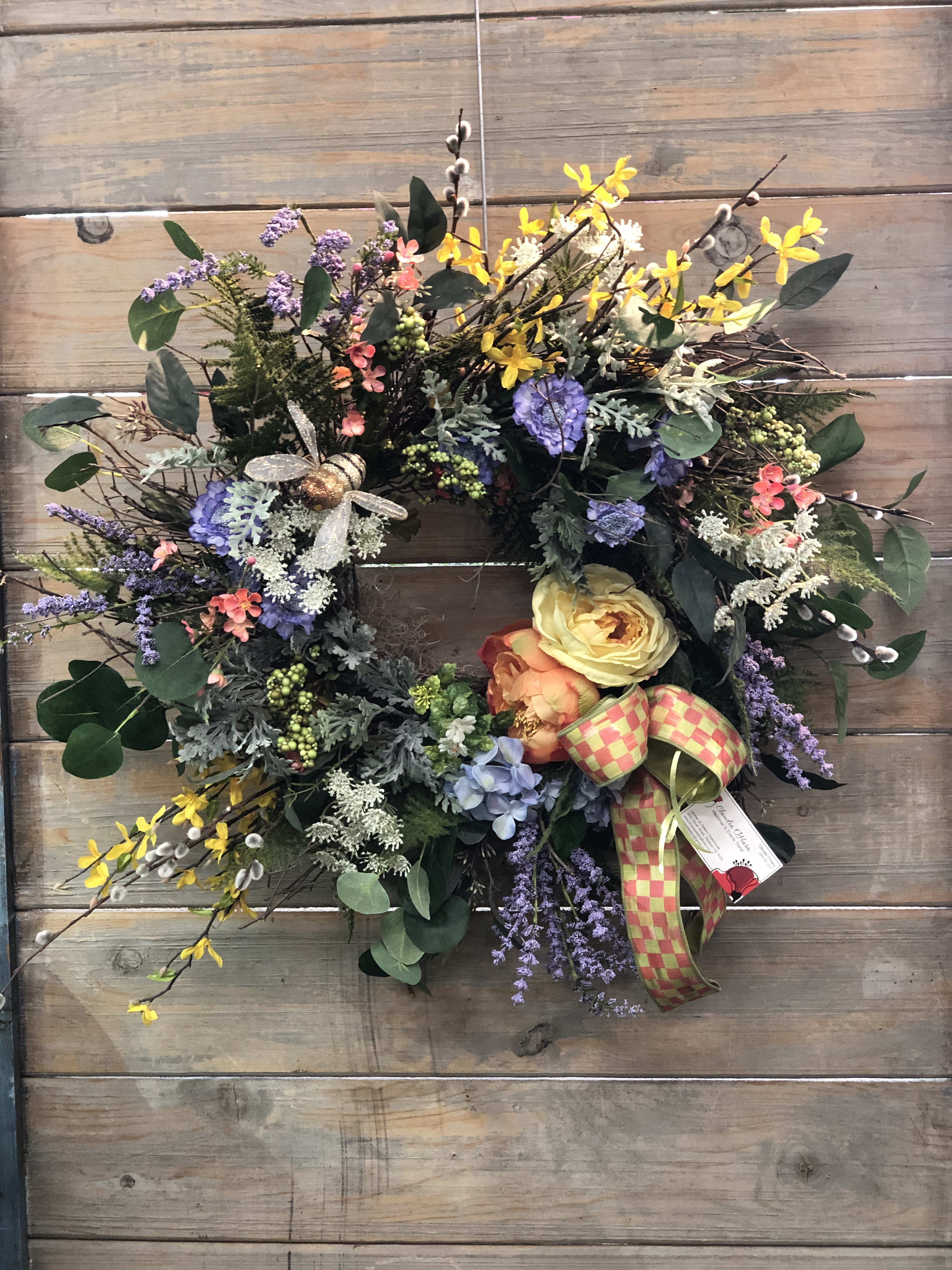 Colorful floral wreath with yellow, purple, and peach blooms on a wood background