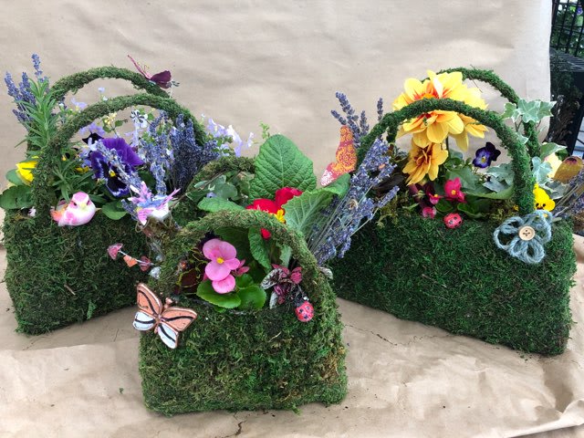 Three moss-covered baskets with colorful flowers and butterfly decorations