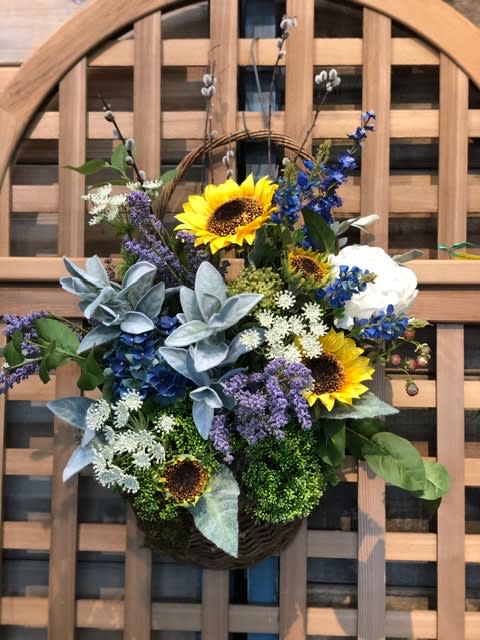 Basket arrangement with sunflowers, blue flowers, and white blooms