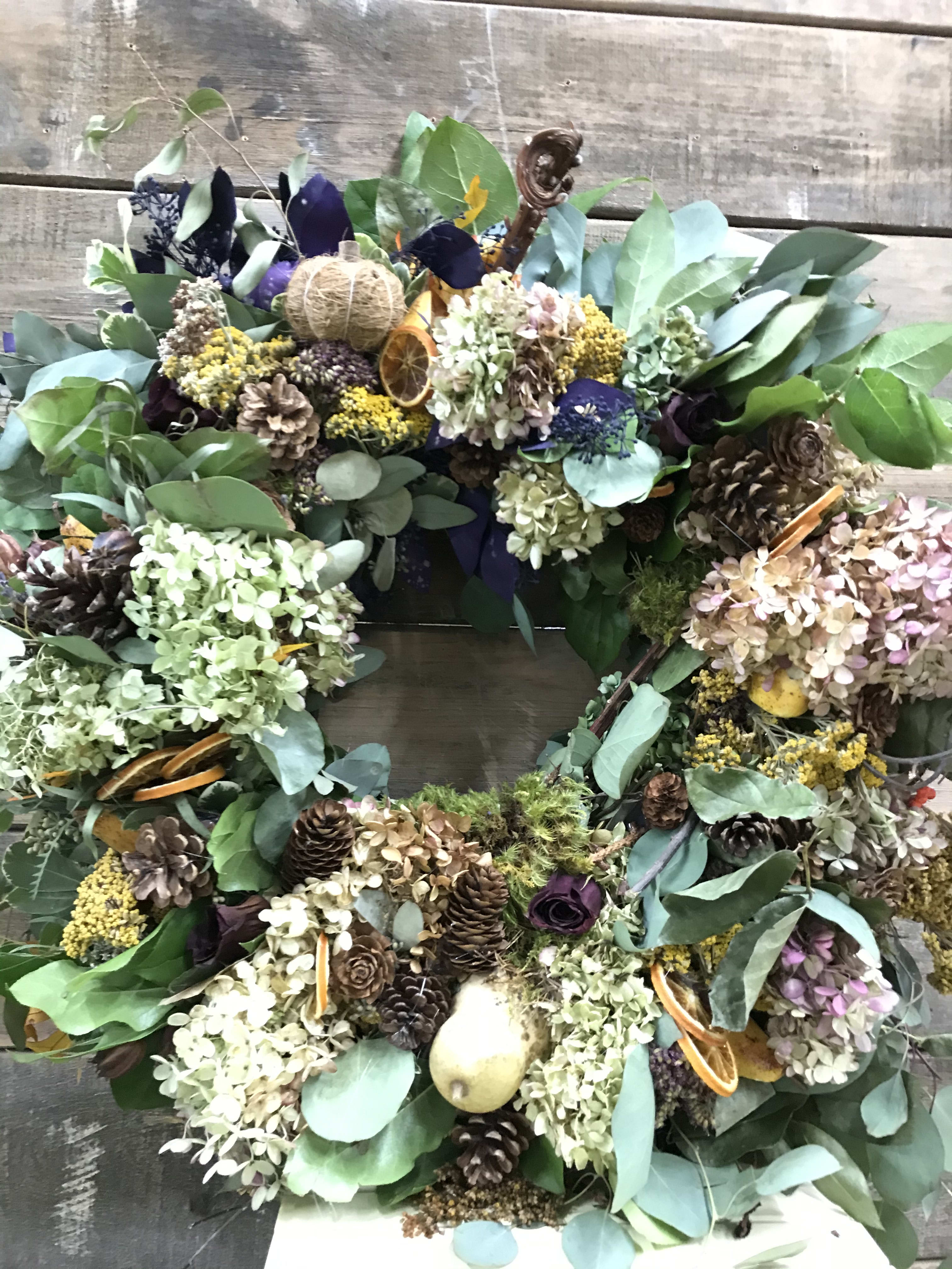 Large wreath with dried flowers, pinecones, and eucalyptus on a wooden background