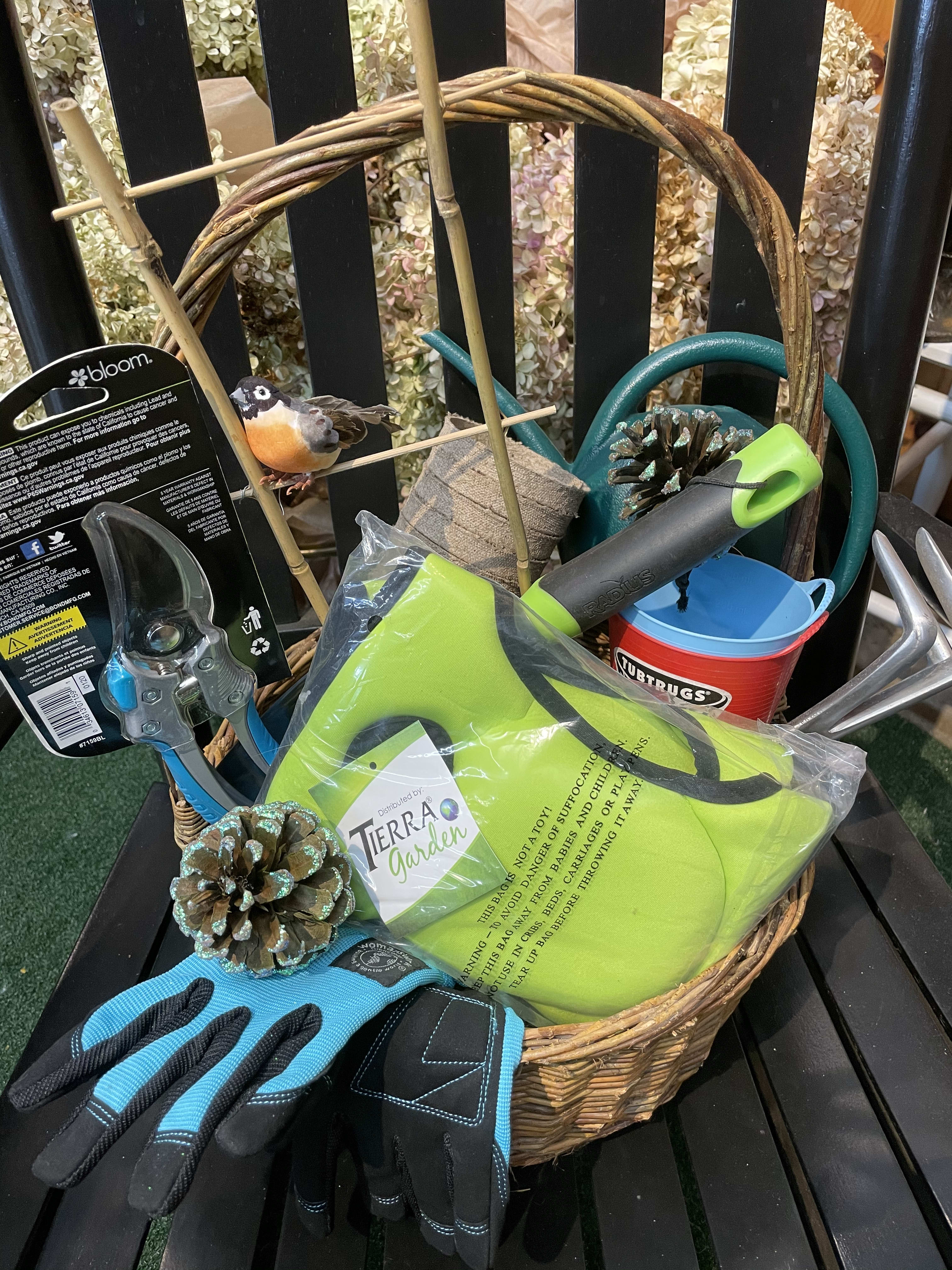 Basket of gardening tools and gloves with a small bird ornament
