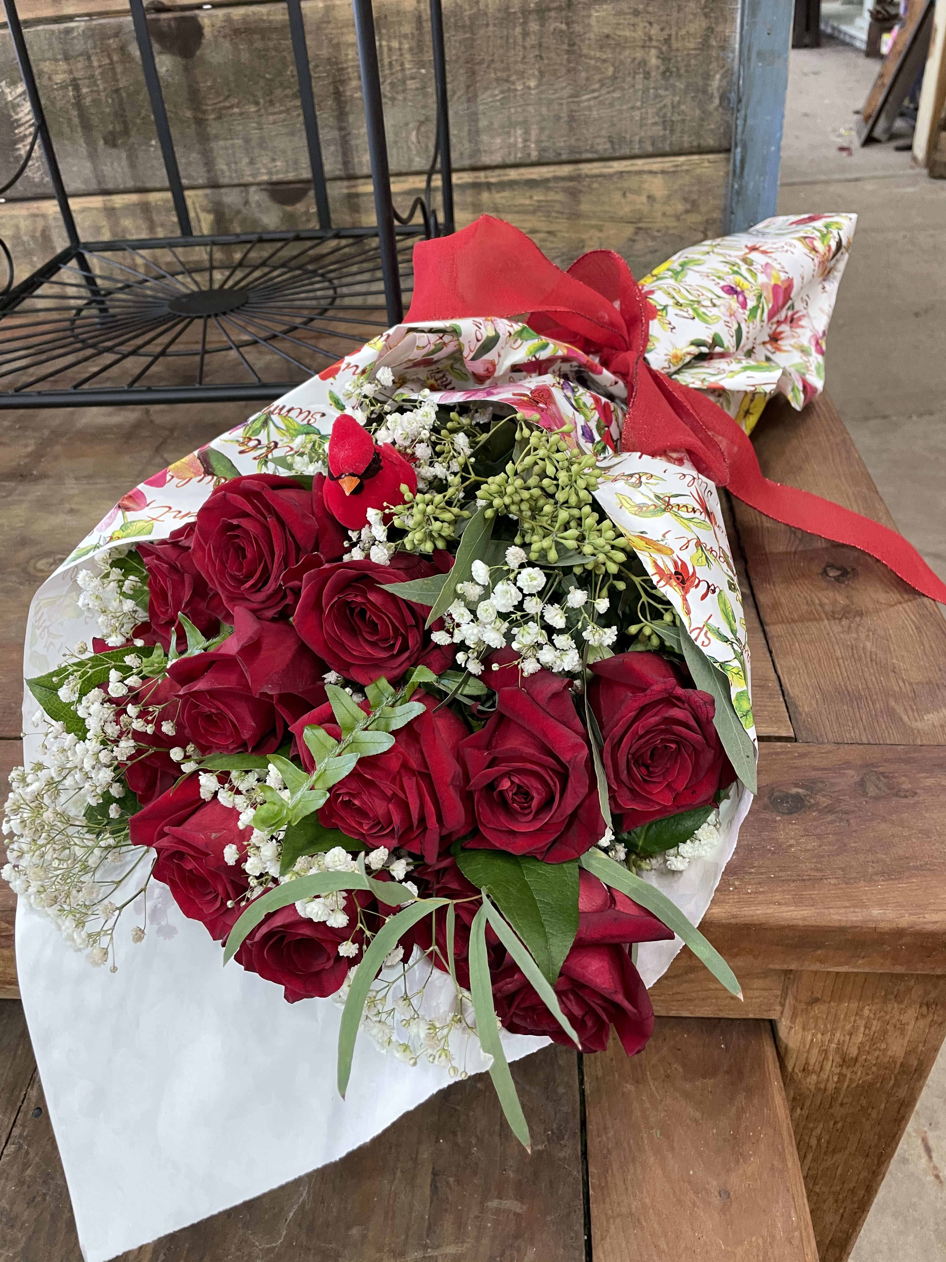 Bouquet of red roses with baby's breath wrapped in floral paper and tied with a red ribbon