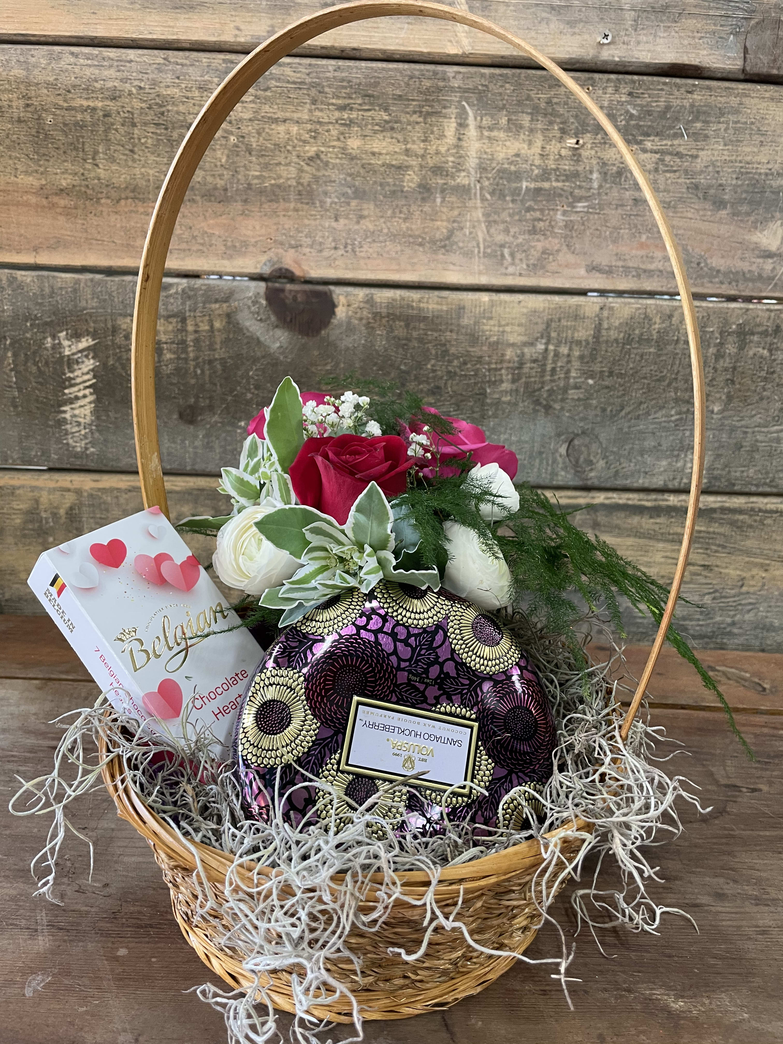 Basket of red and white roses with chocolates and a heart-shaped gift