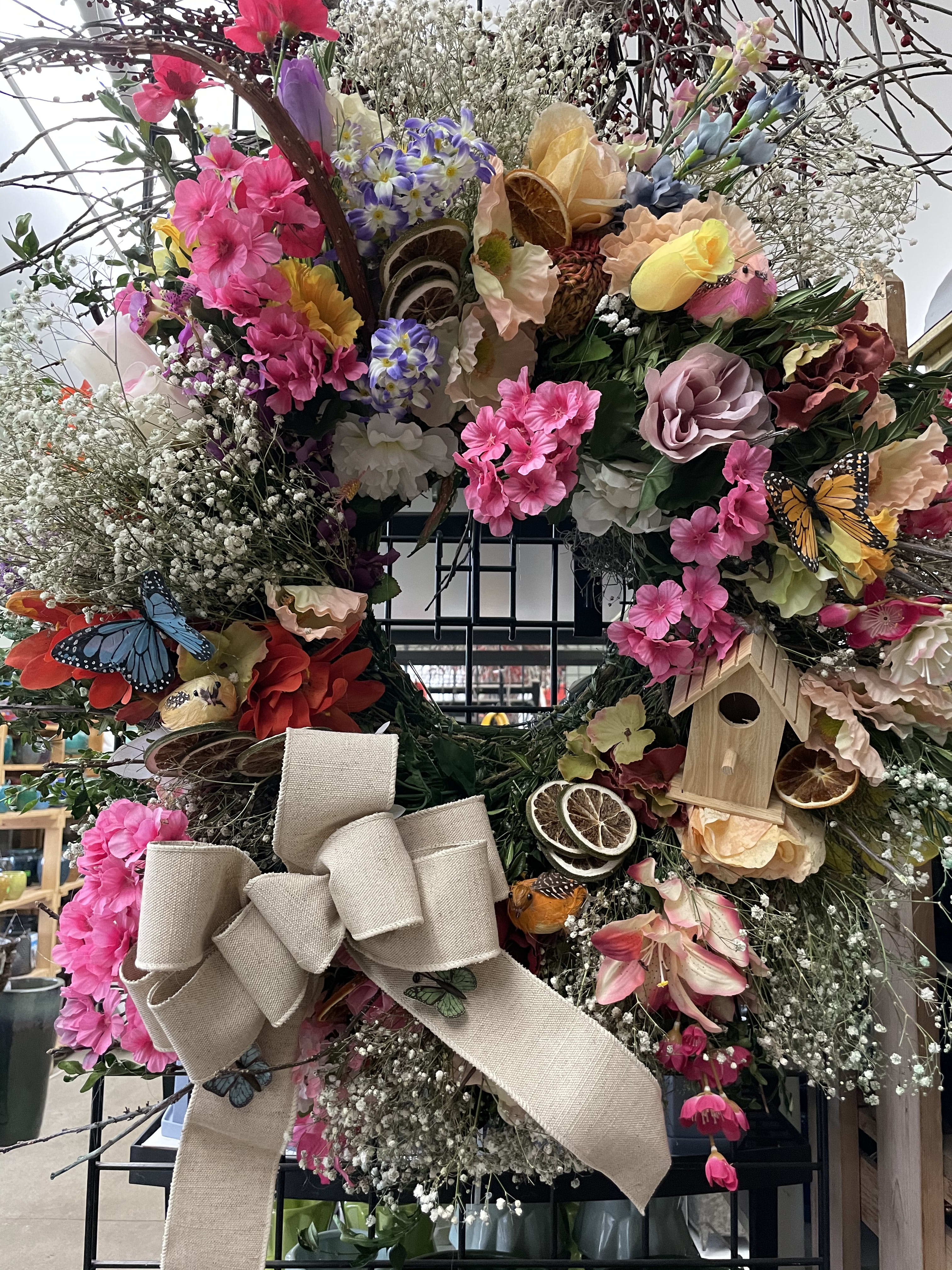 Large floral wreath with pink blooms, butterflies, and a burlap bow