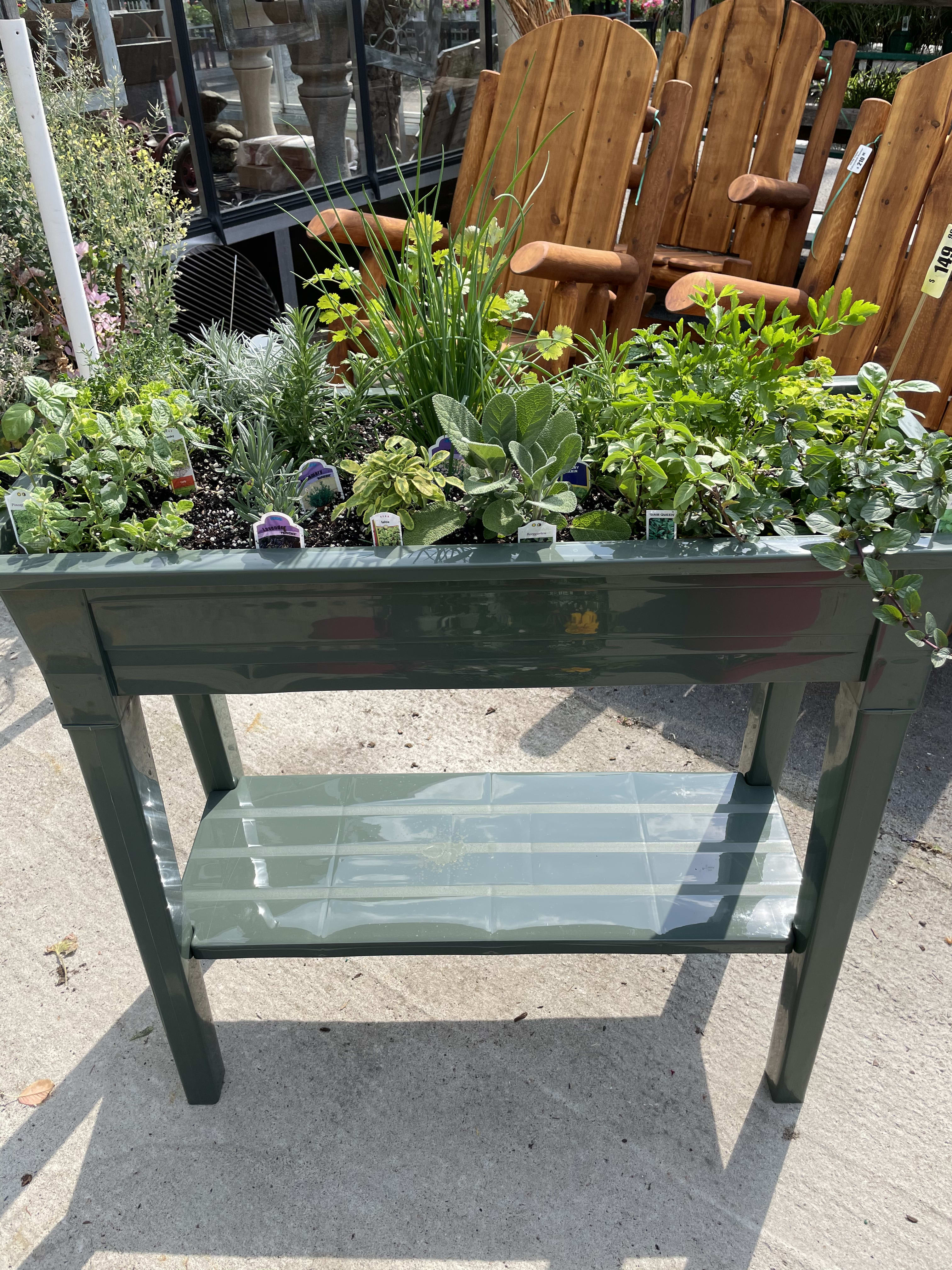 Outdoor planter table filled with assorted green herbs and plants