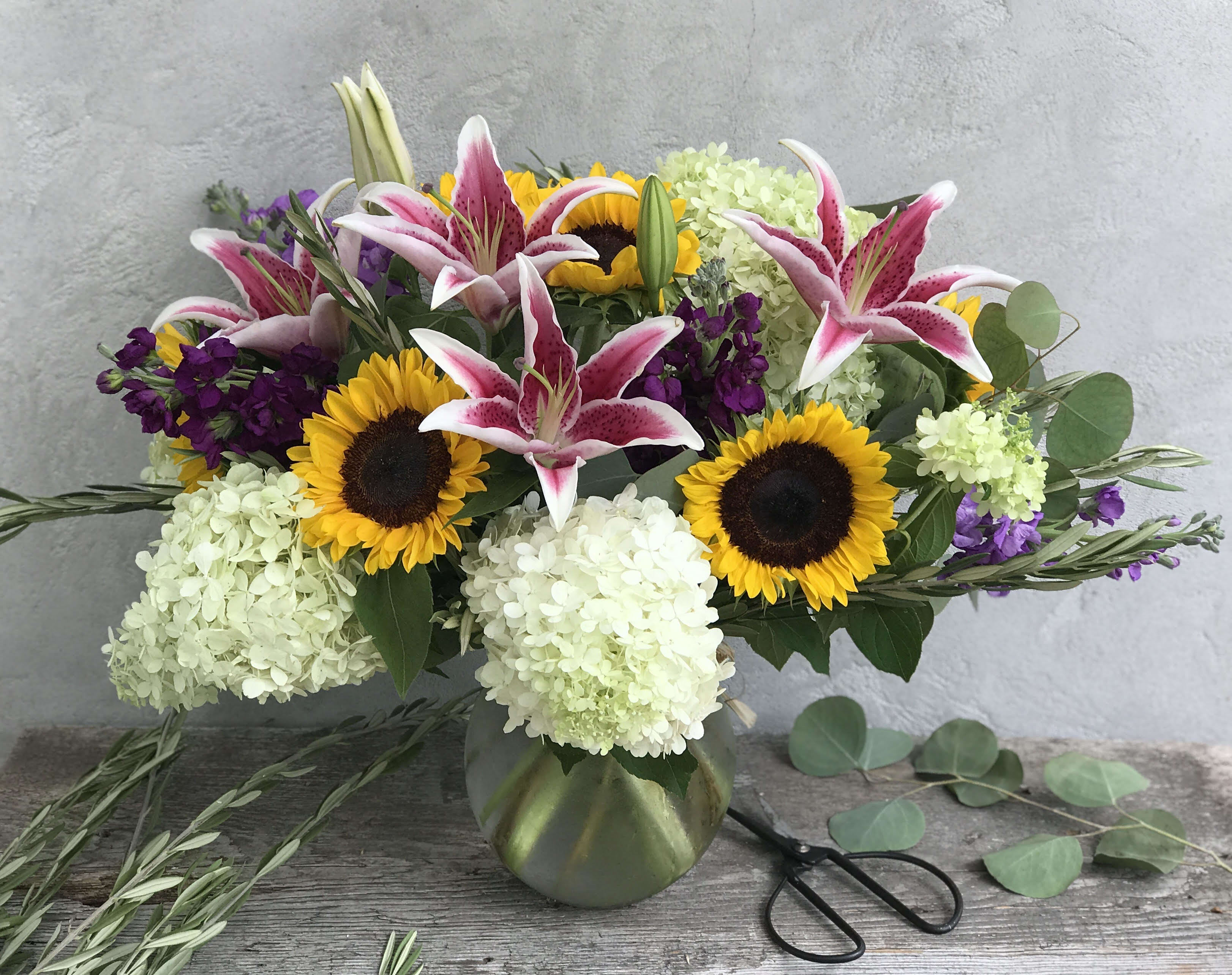 Bouquet of pink lilies, sunflowers, and white hydrangeas in a vase