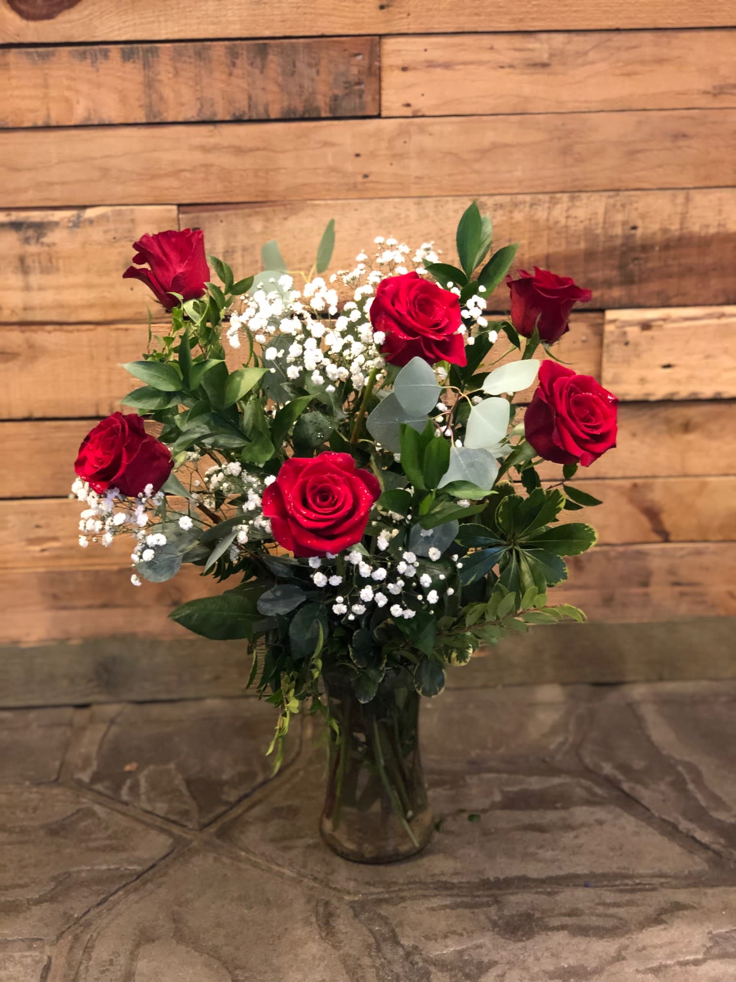 Red roses arranged in a clear glass vase with white baby's breath