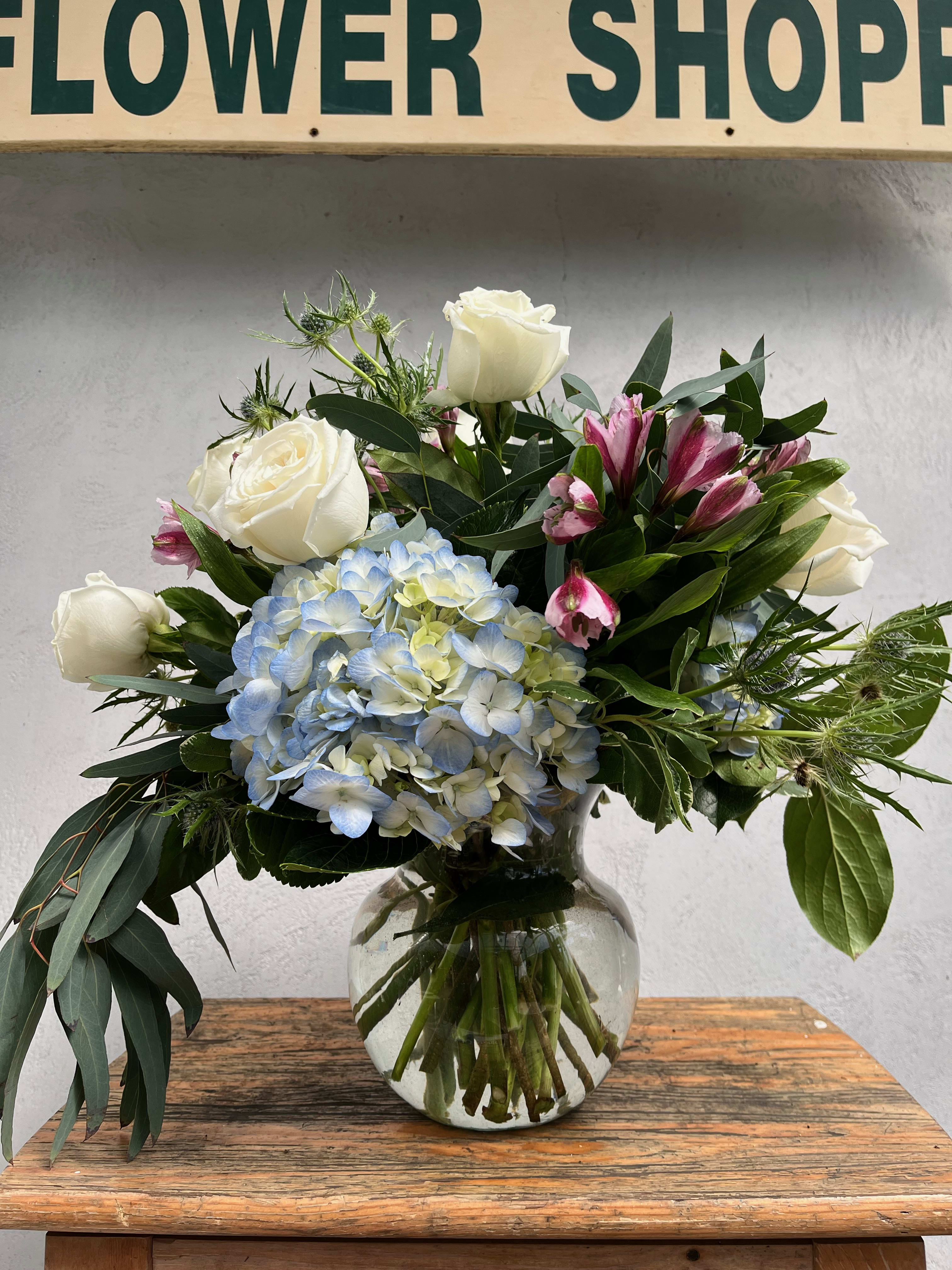 White roses and blue hydrangea in a glass vase