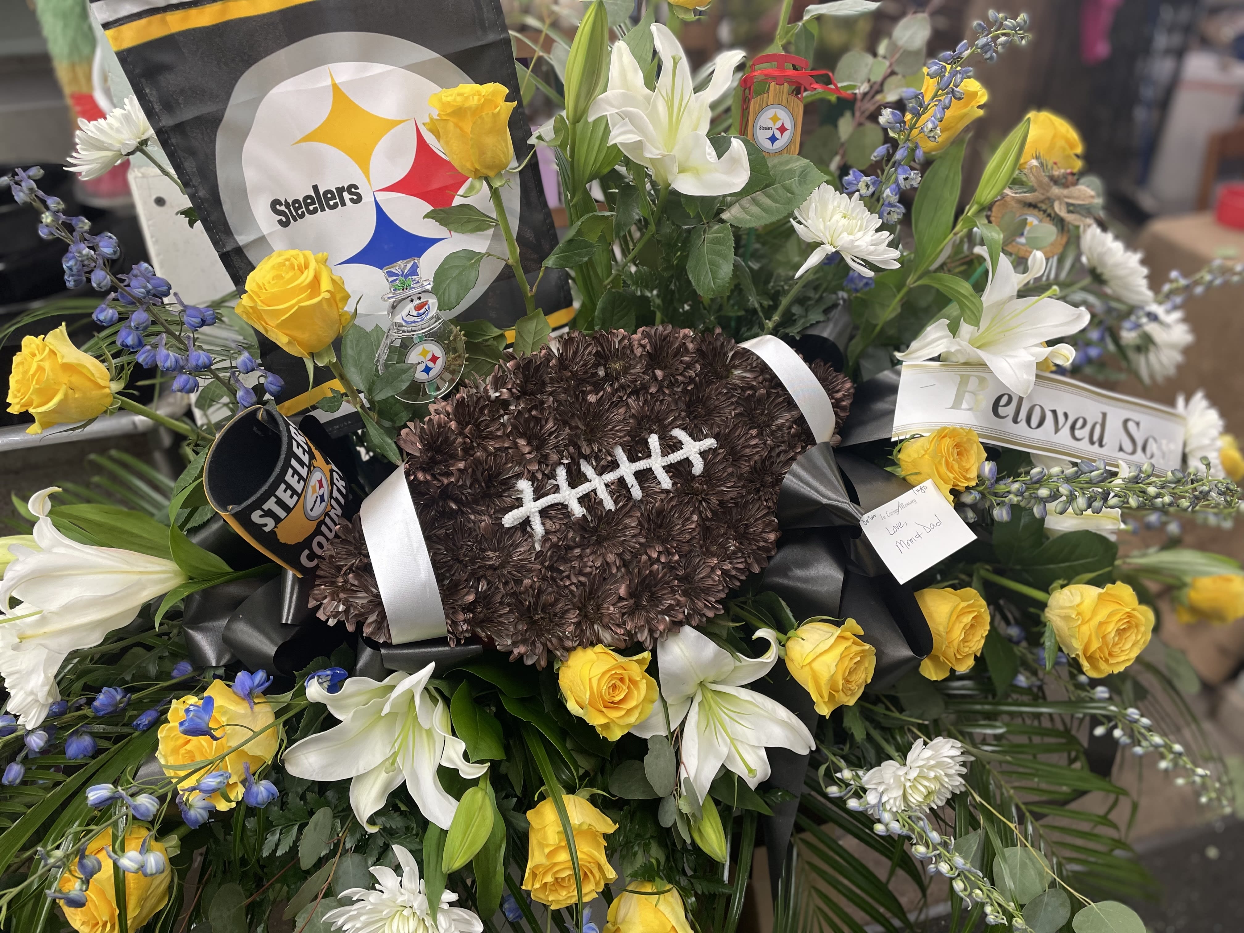 Football-shaped floral tribute with yellow roses and white lilies