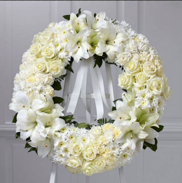 White floral wreath with roses and lilies on a stand