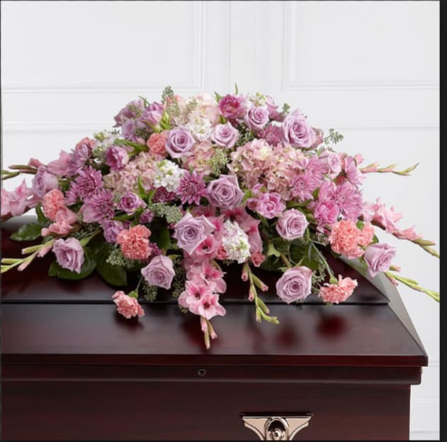 Pink and lavender floral spray on a dark casket