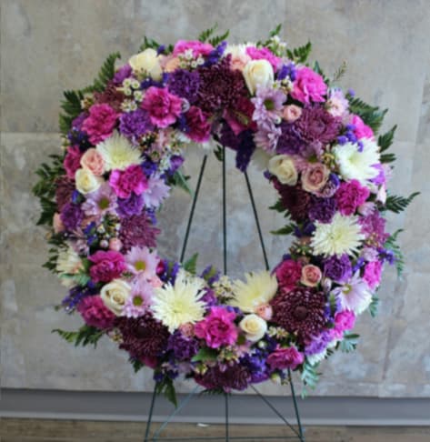Large floral wreath on a stand with pink, purple, and white blooms