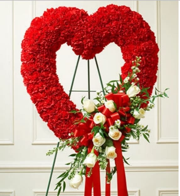Heart-shaped red floral wreath with white roses and a red ribbon bow