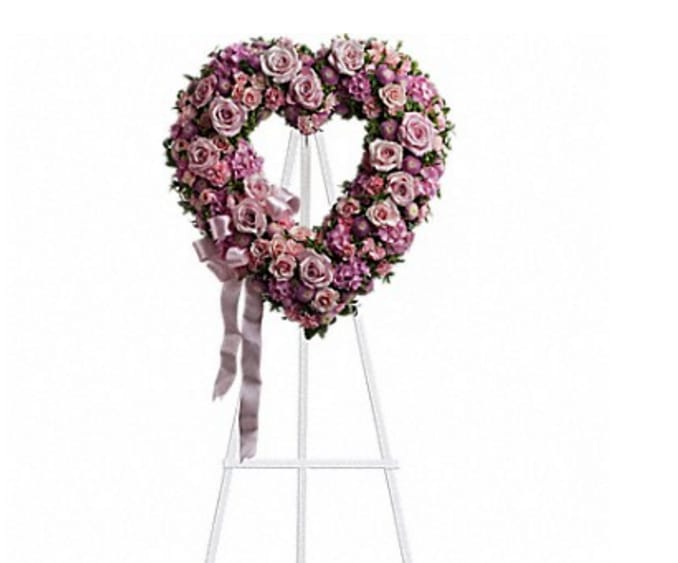 Heart-shaped pink and lavender rose wreath on an easel with ribbon