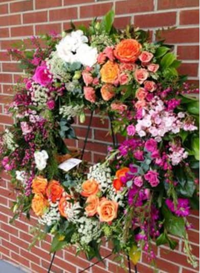 Large floral wreath with orange, pink, and white flowers on a stand