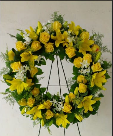 Yellow floral wreath with roses and lilies on a stand
