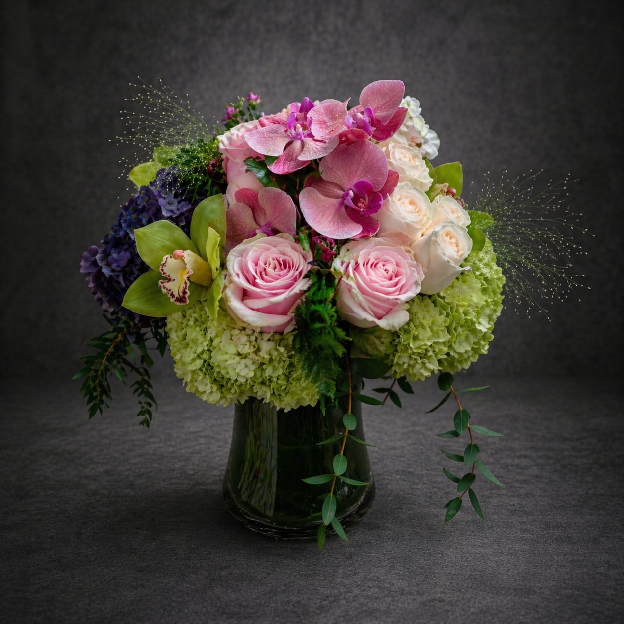 Pink and white floral arrangement in a dark glass vase