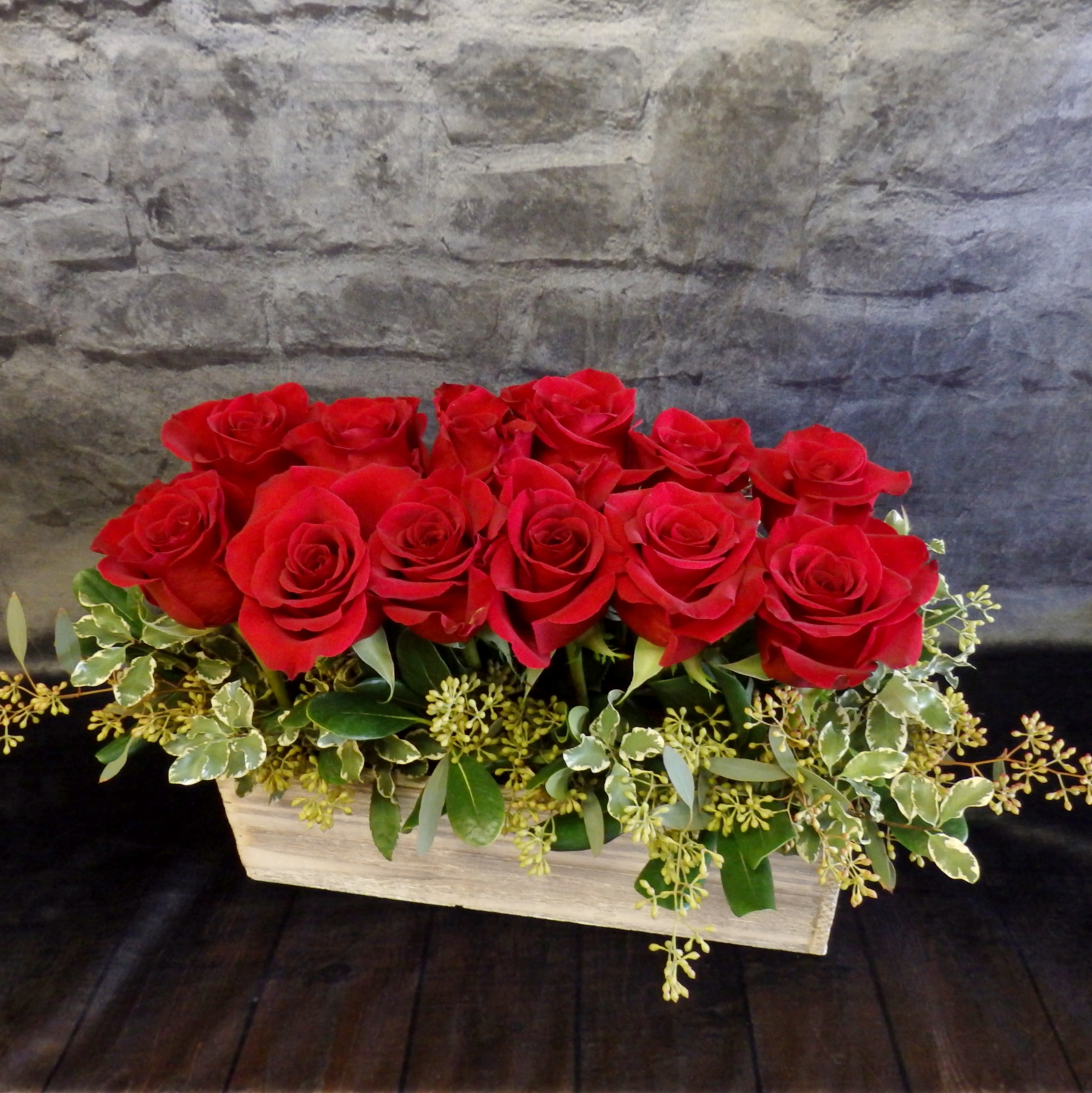 Red roses arranged in a low rectangular wooden container