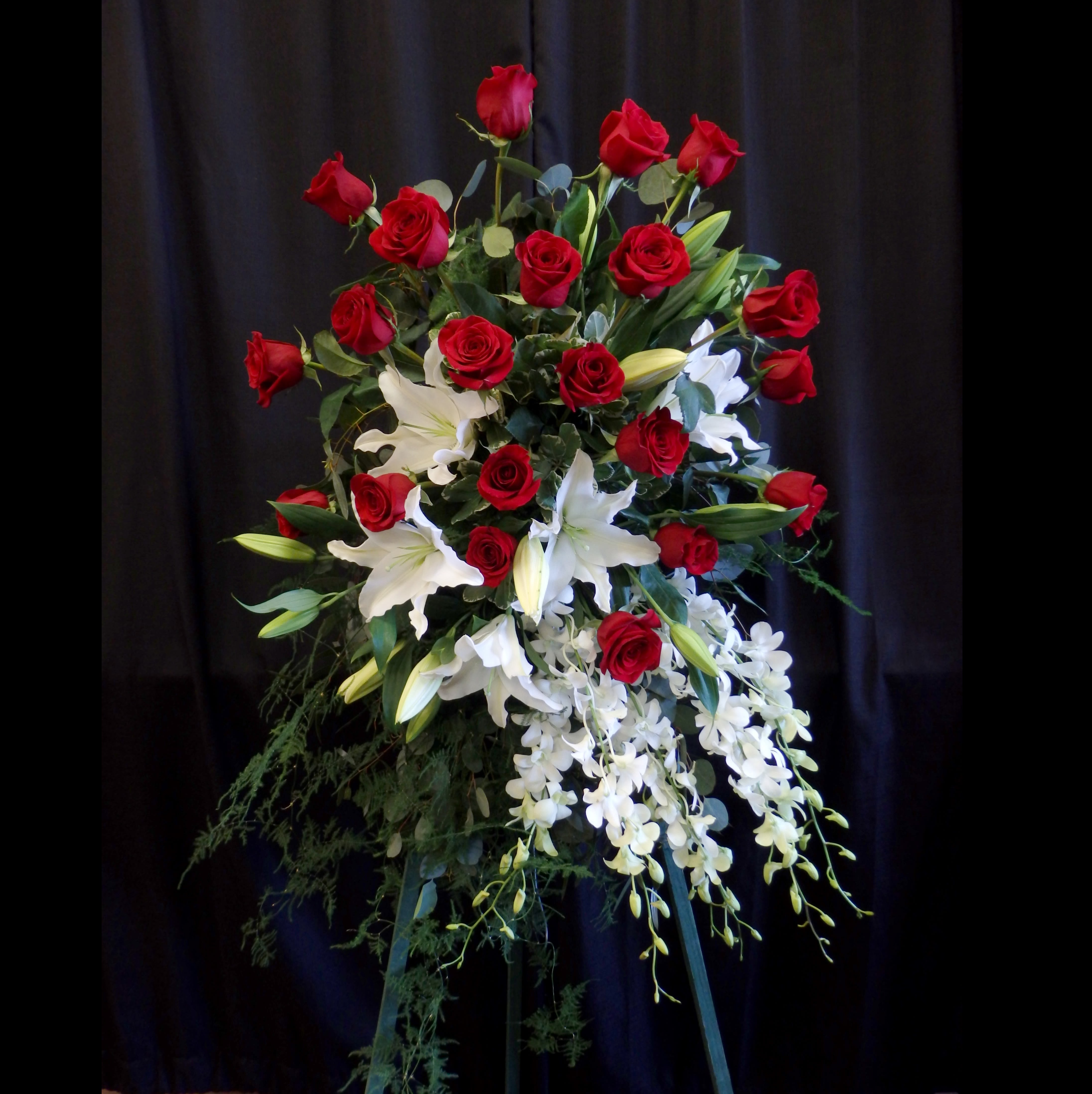 Standing floral spray of red roses, white lilies, and white orchids